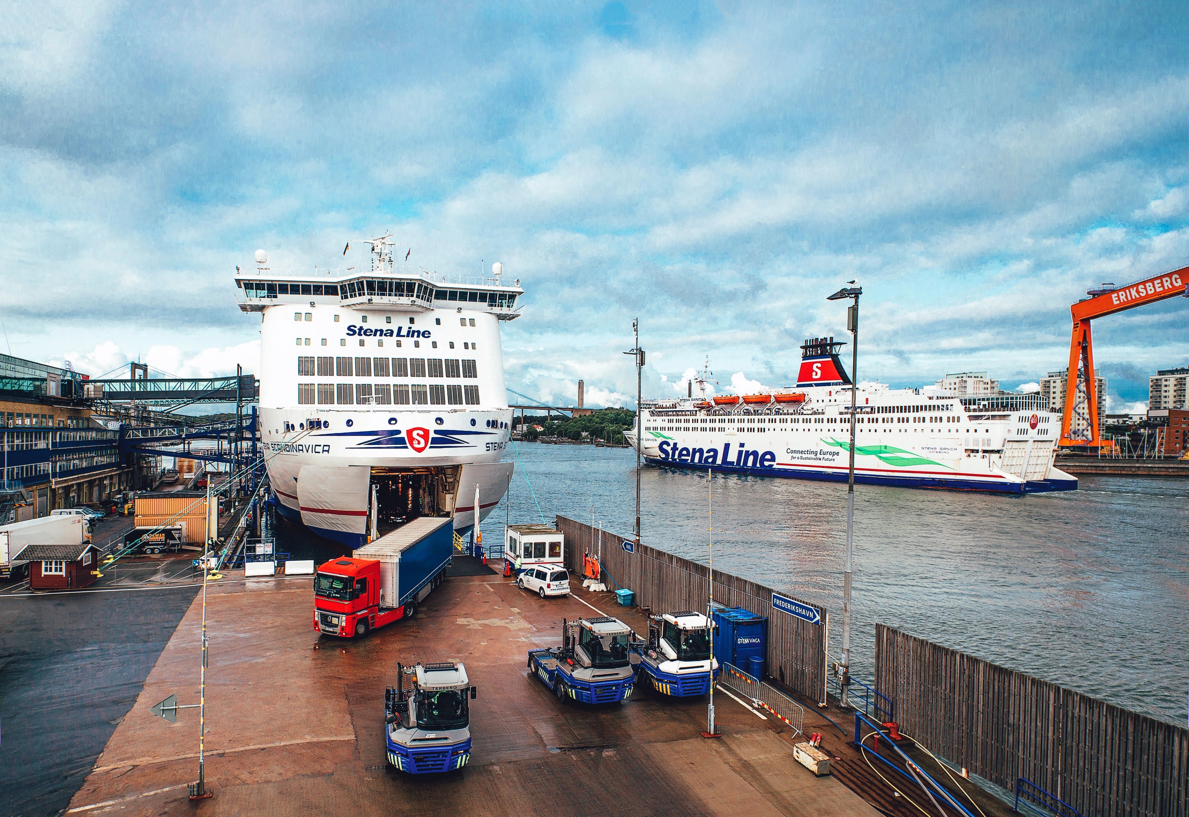 Ferries docked at a port with trucks and cargo operations underway.