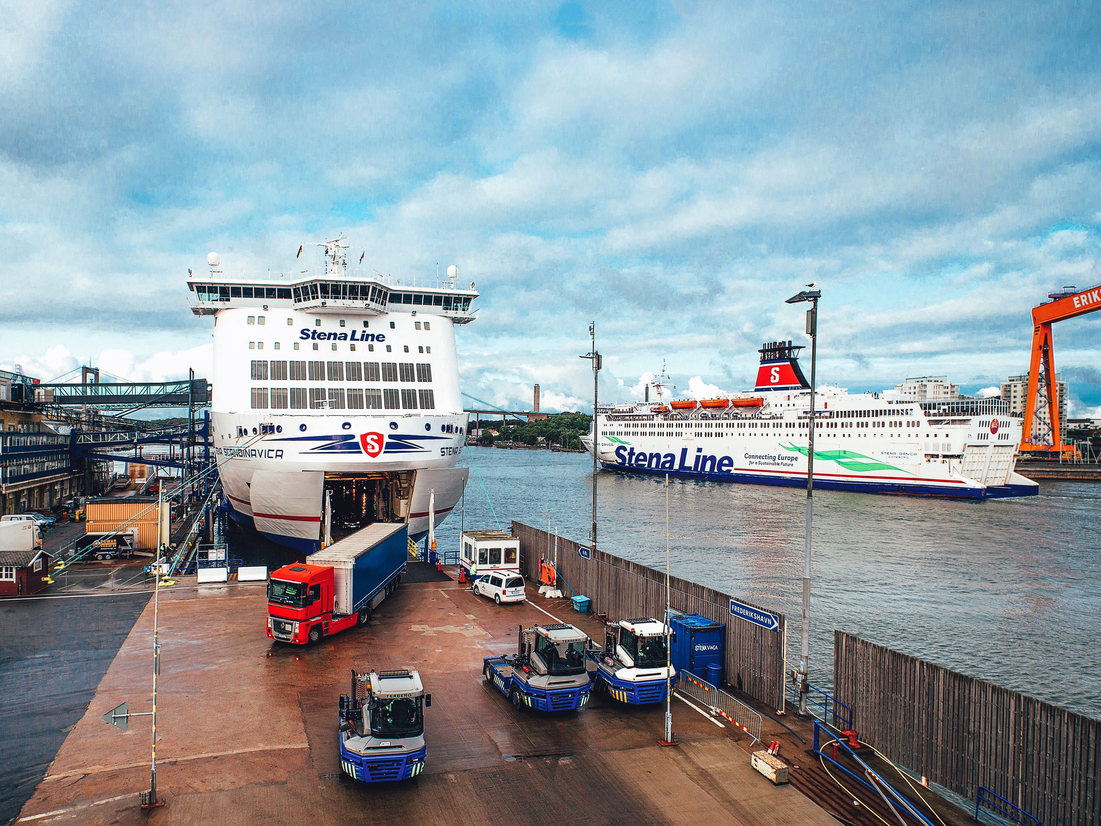 Ferries docked at a port with trucks and cargo operations underway.