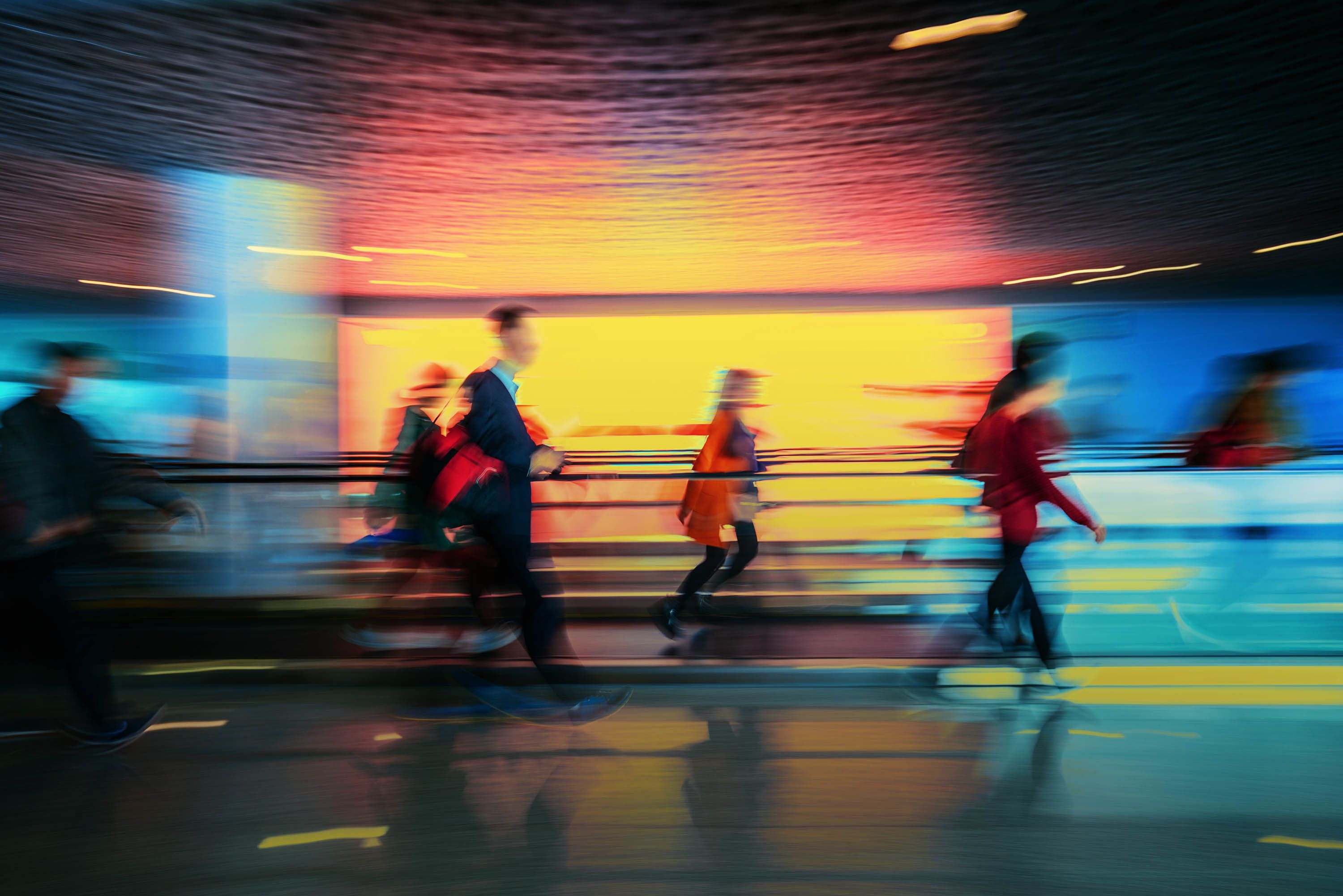 People walking in front of a blurred colorful background