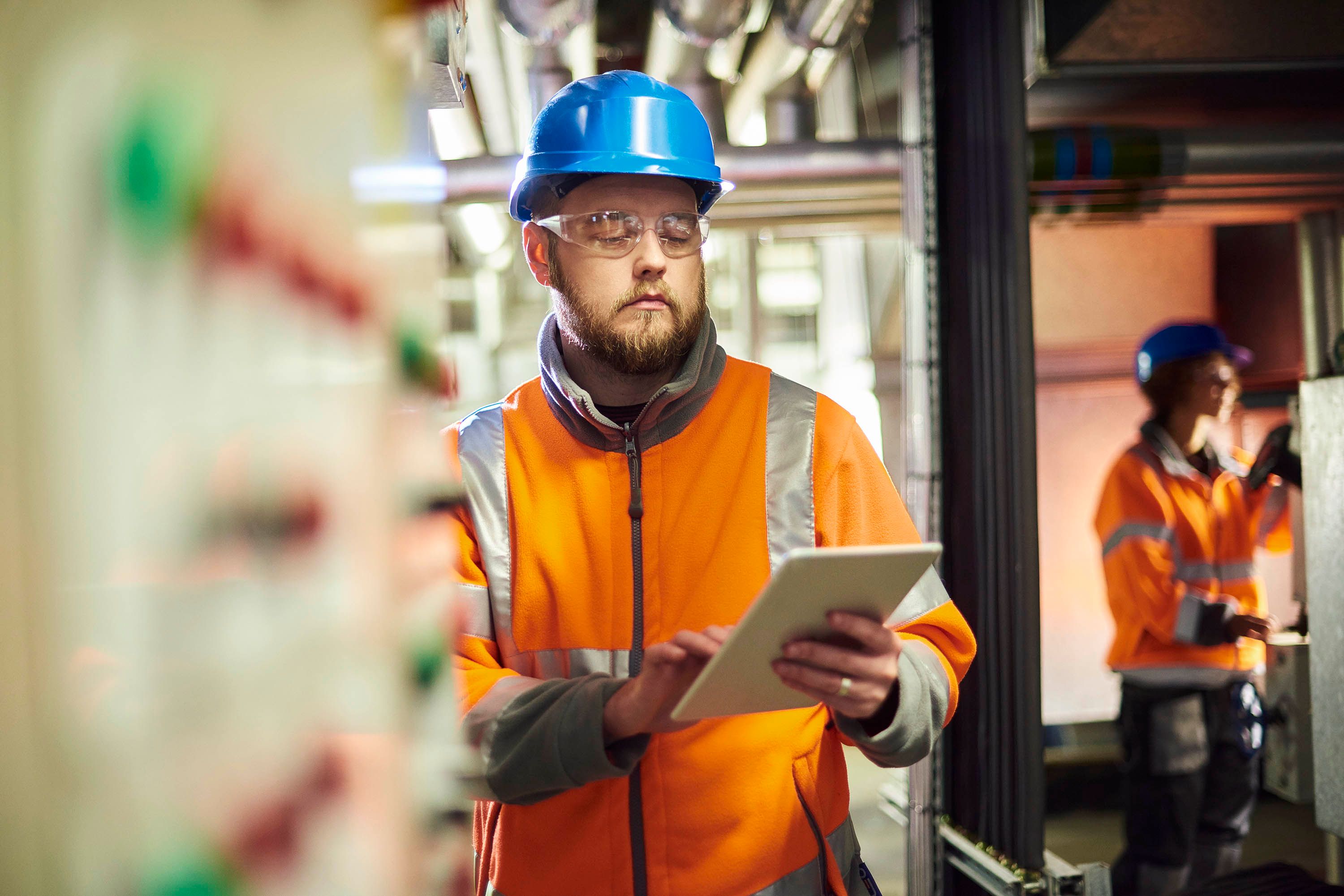 An industrial worker holding a notepad in a factory