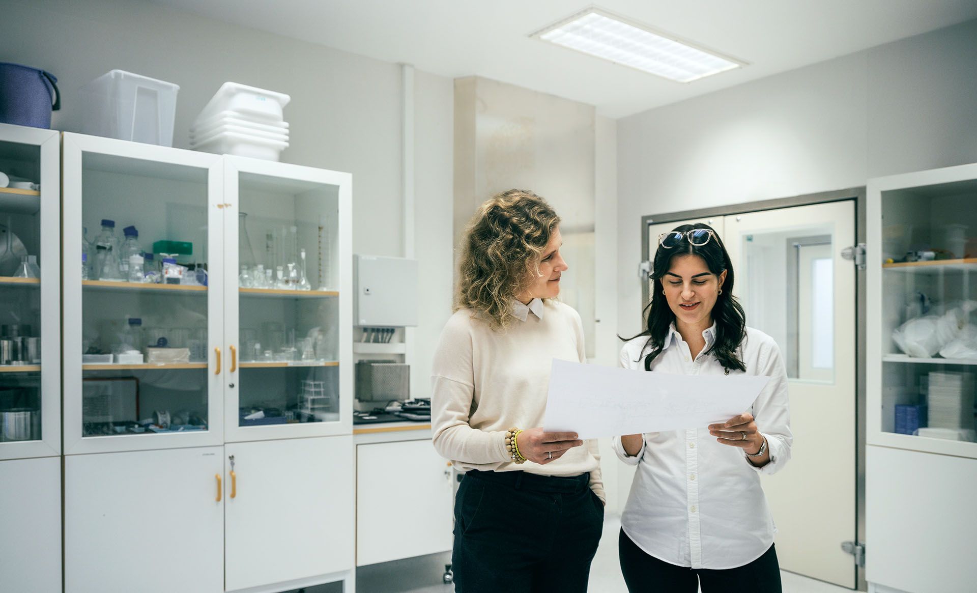 Two women in a laboratory environment reviewing a document