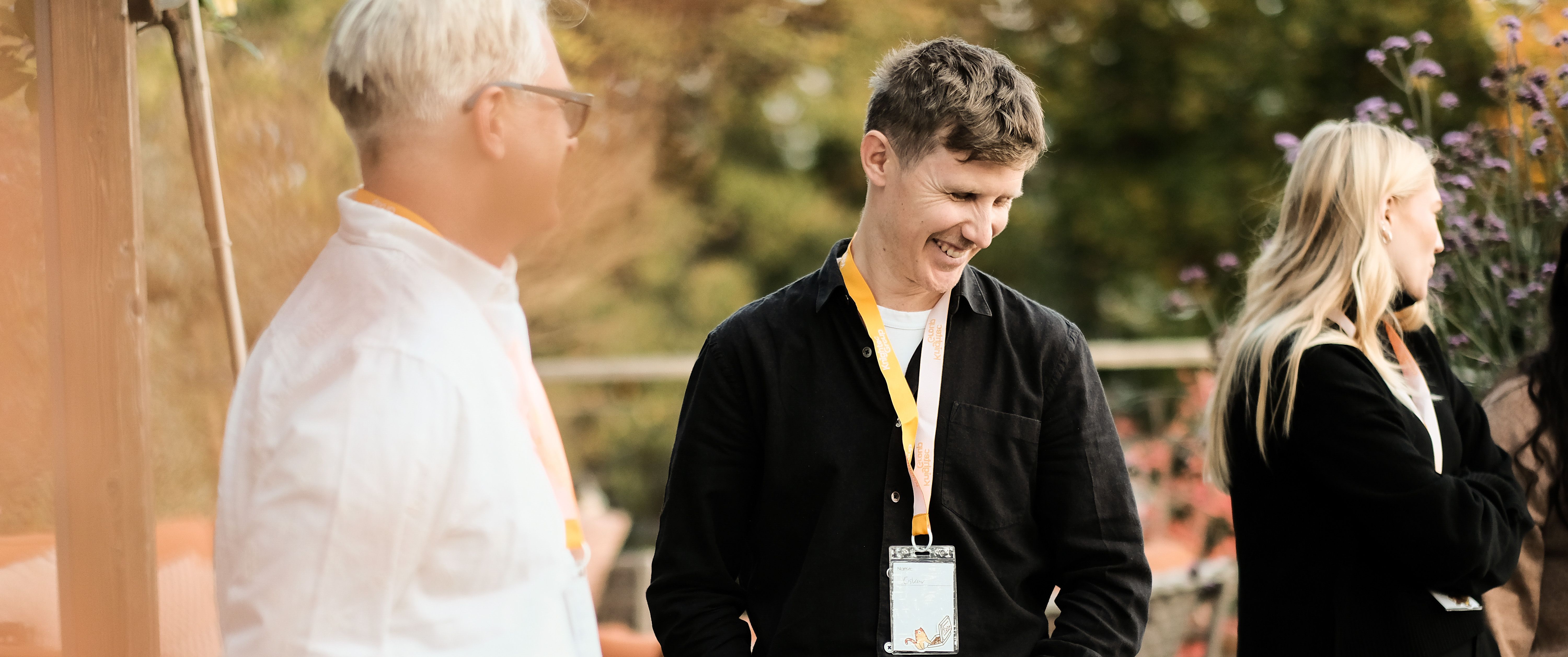 Three people standing in an outside setting at an event
