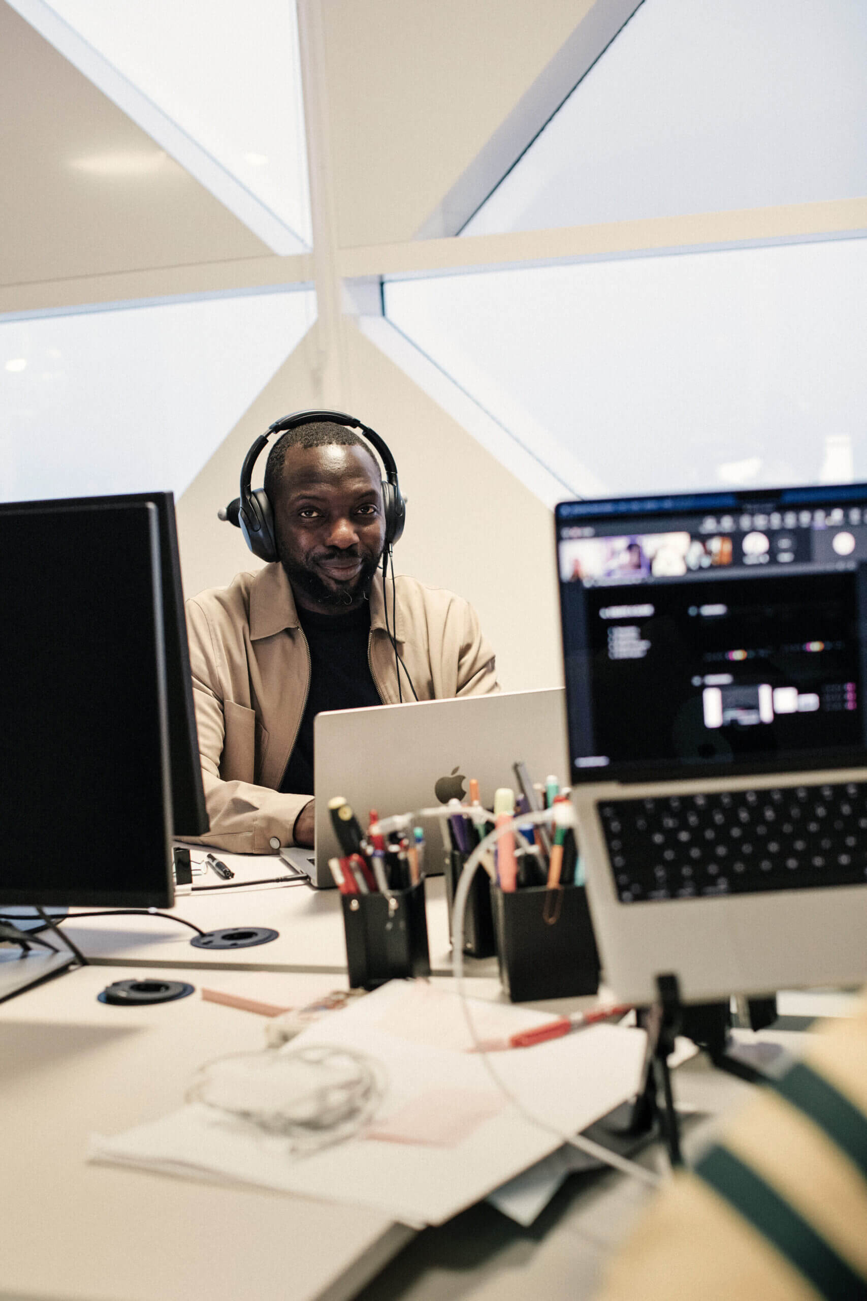 Two computer screens and a person sitting behind a laptop