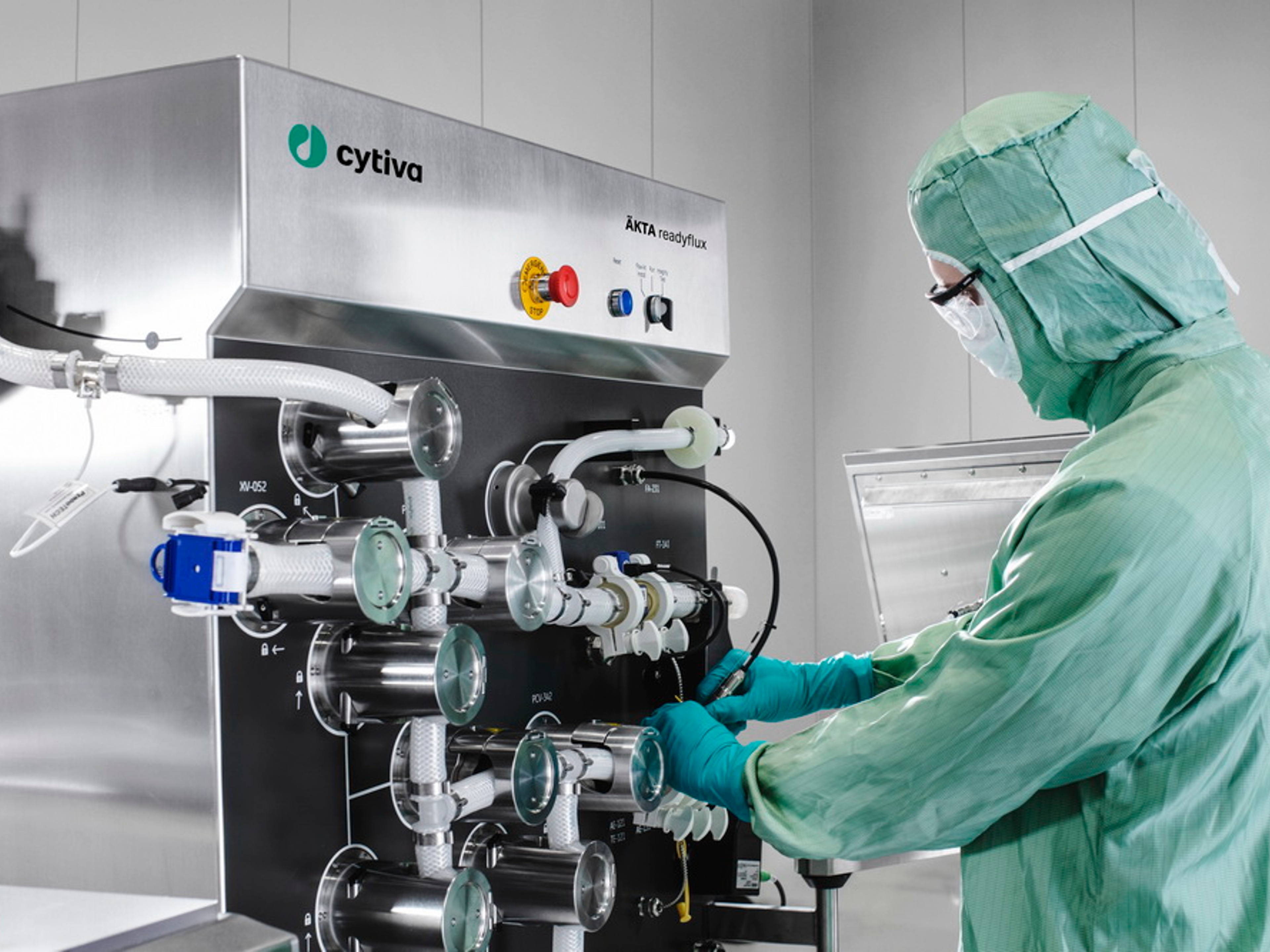 A person in protective clothes by a Cytiva machine