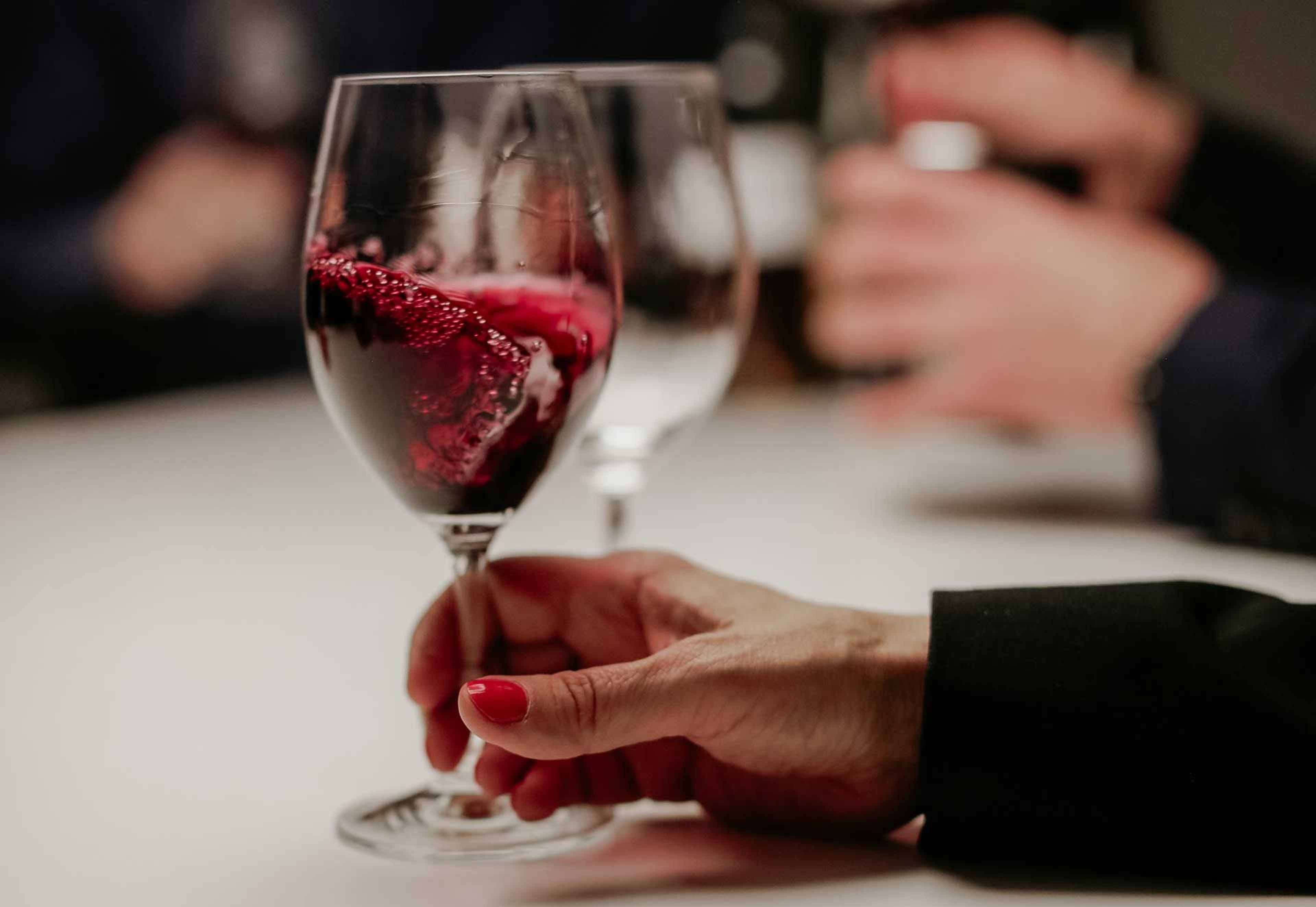 Image of a hand holding a glass of wine