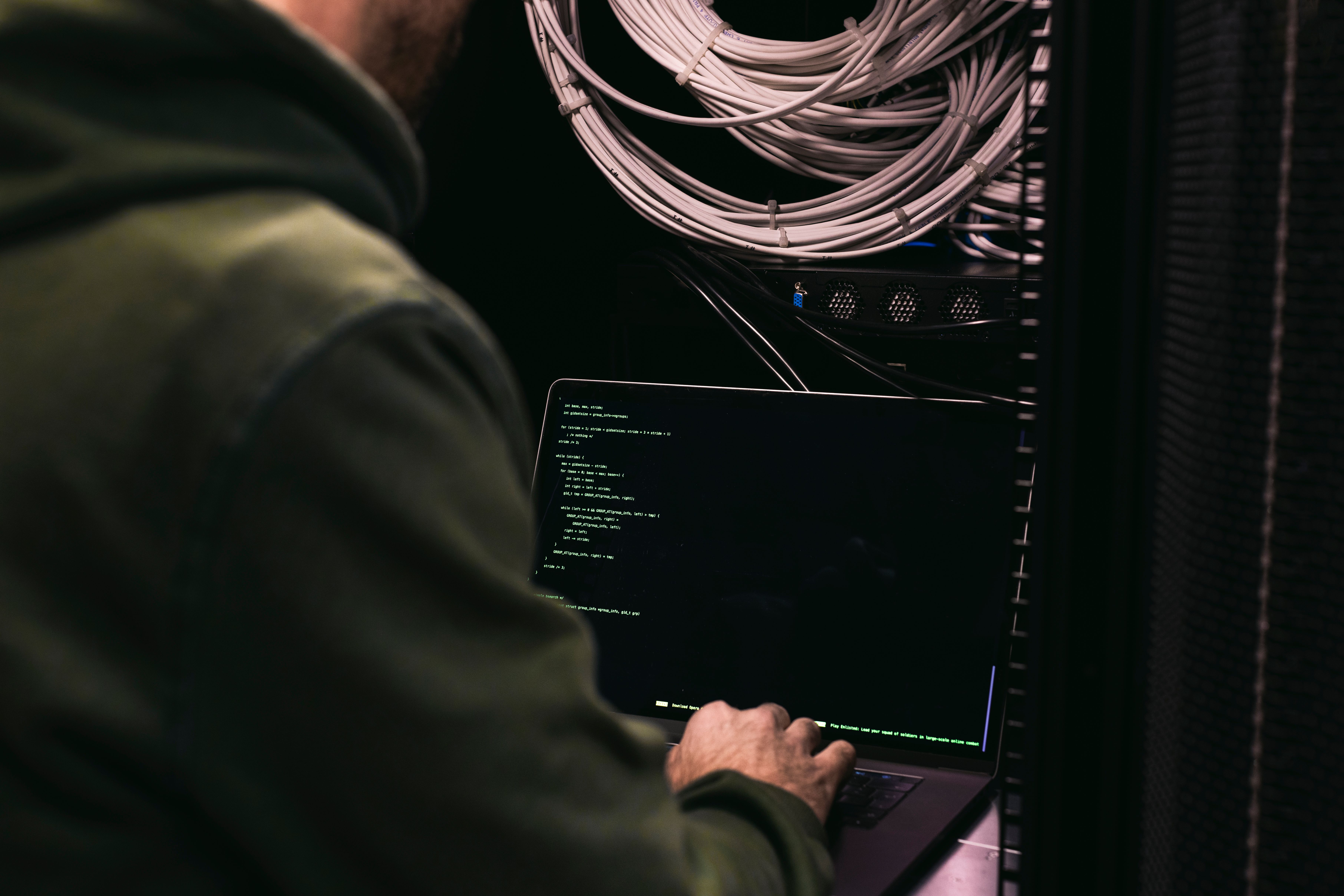 A man sitting in front of a computer in a server room.
