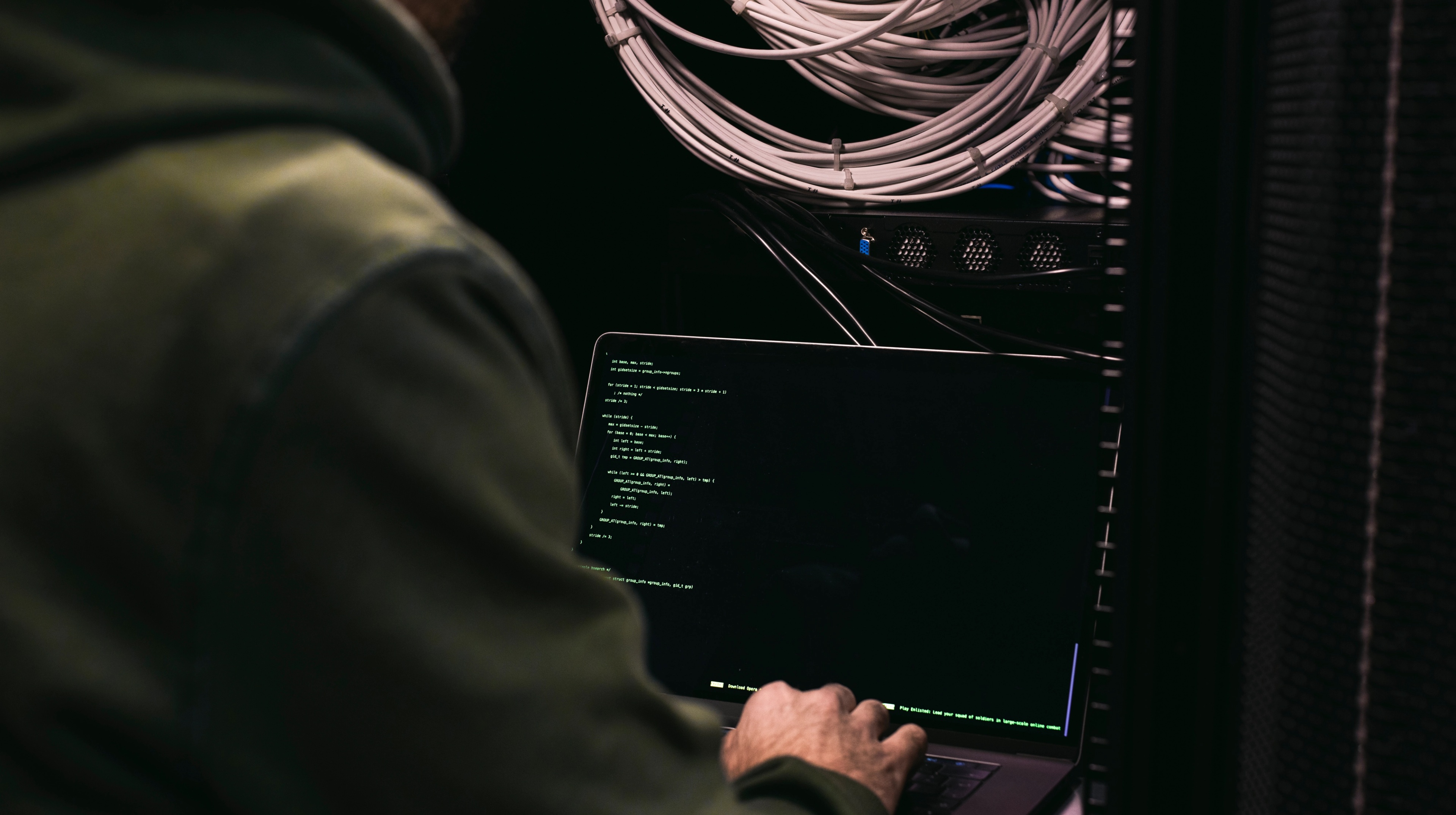 A man sitting in front of a computer in a server room.