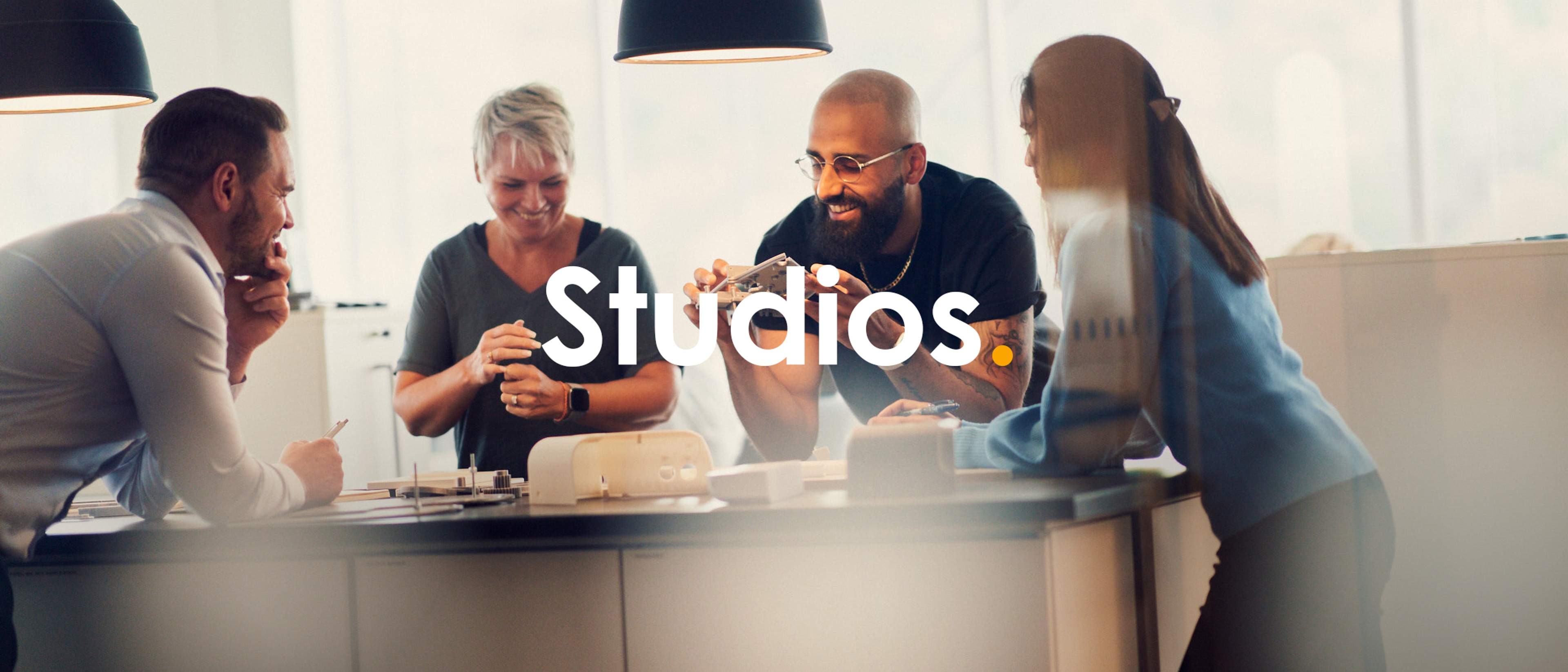 Four people standing around a table at looking at physical prototypes.