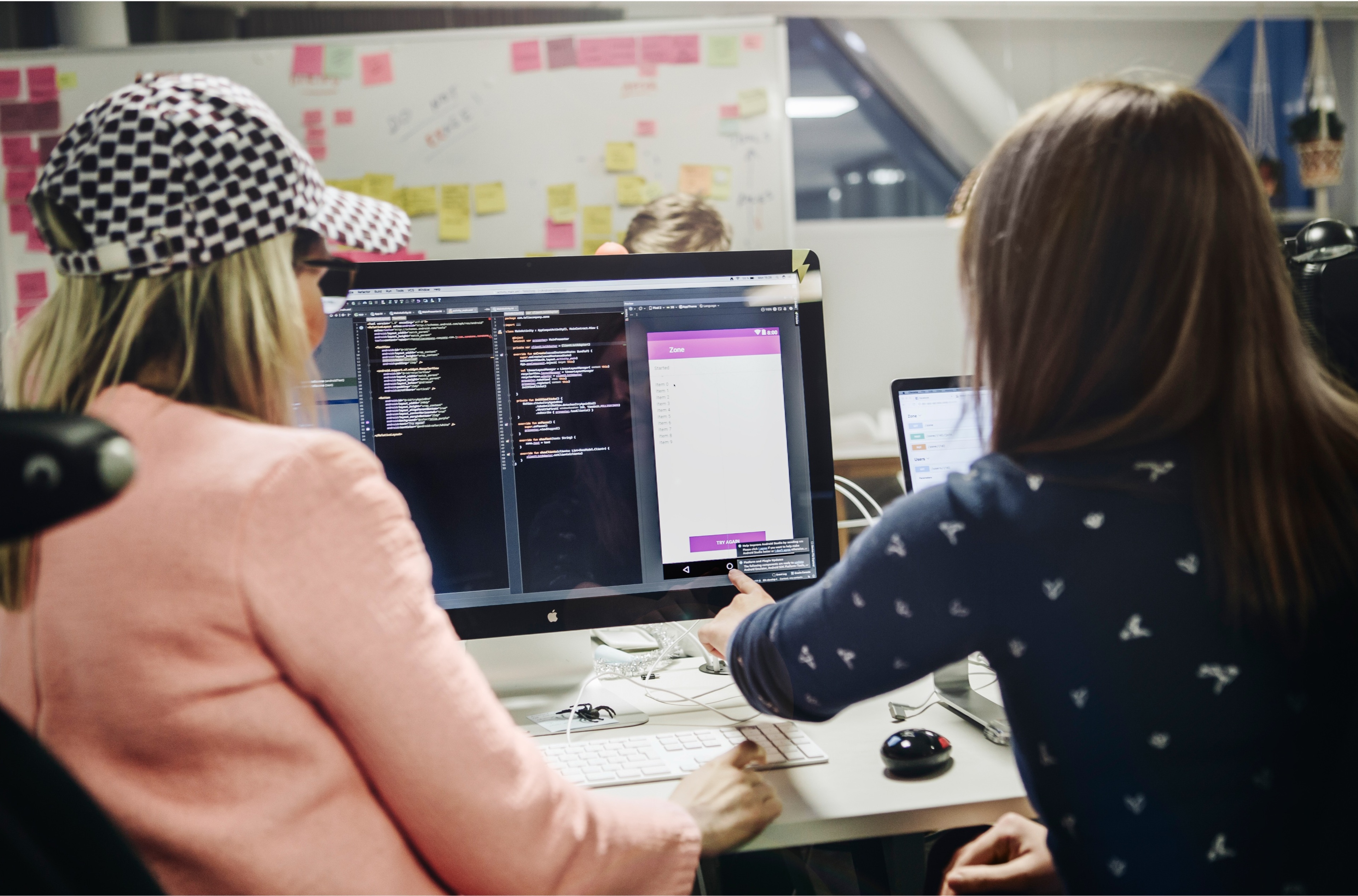 Två kvinnor sitter framför en datorskärm och arbetar med UX.