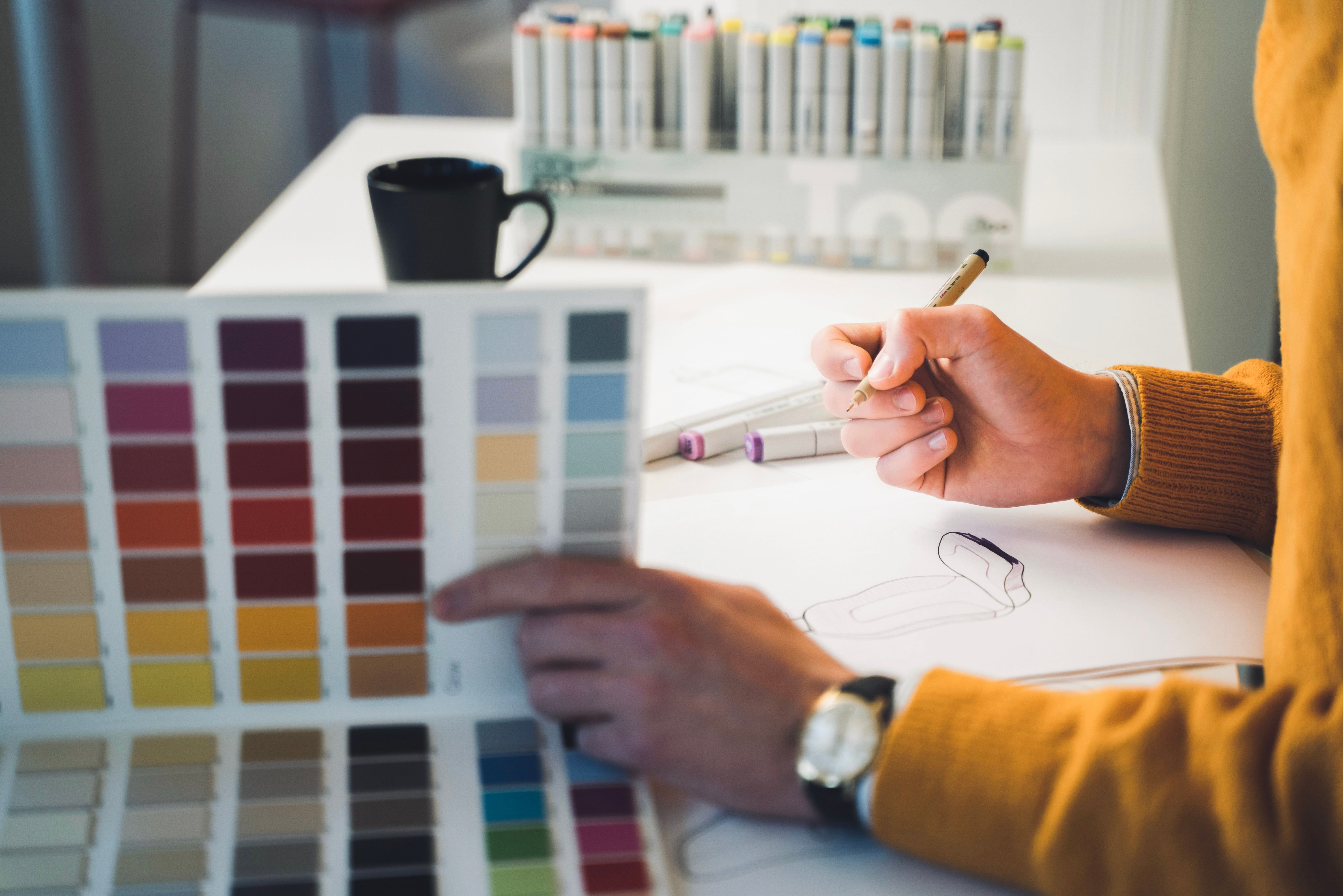 A women sketching on a paper with color palette beside.