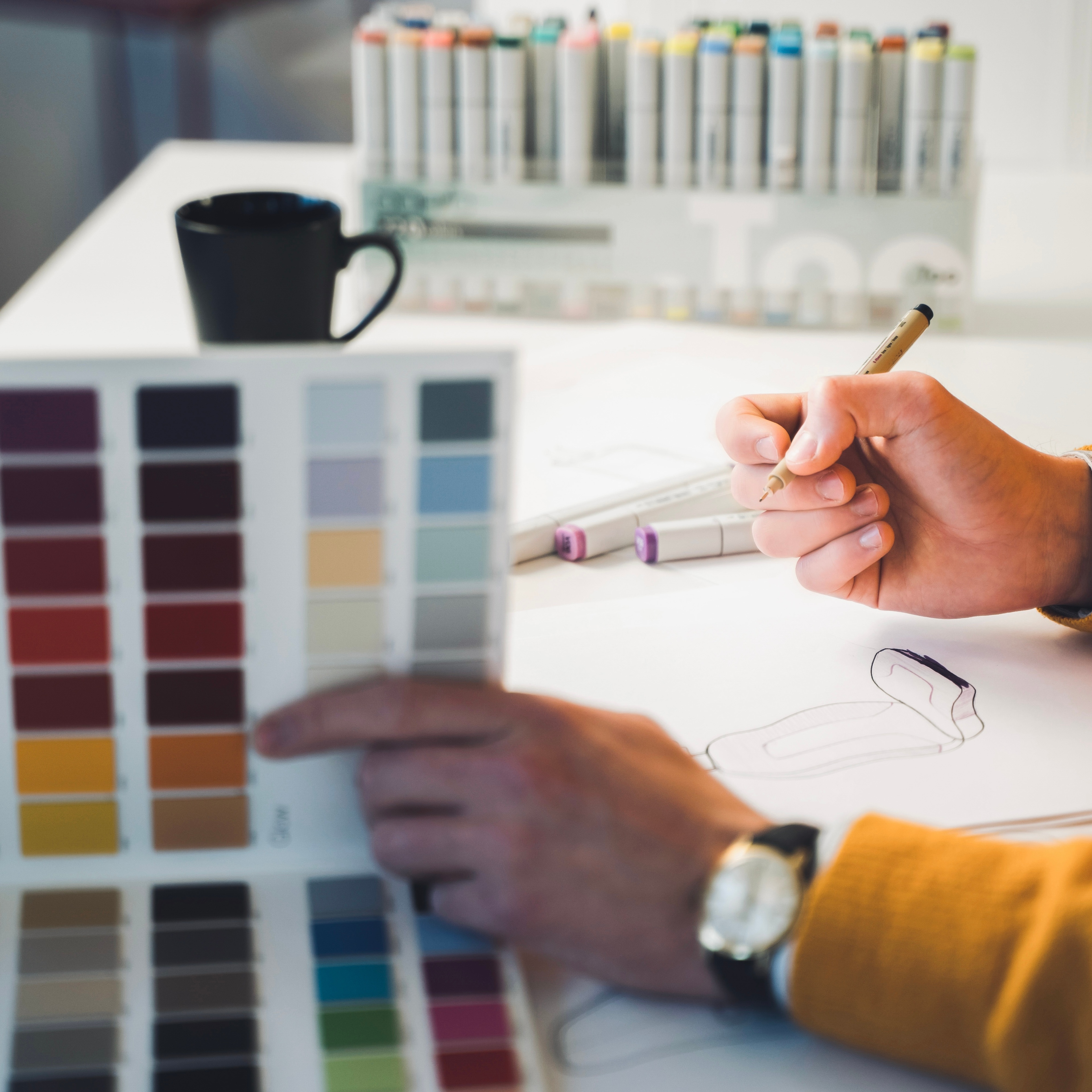 A women sketching on a paper with color palette beside.