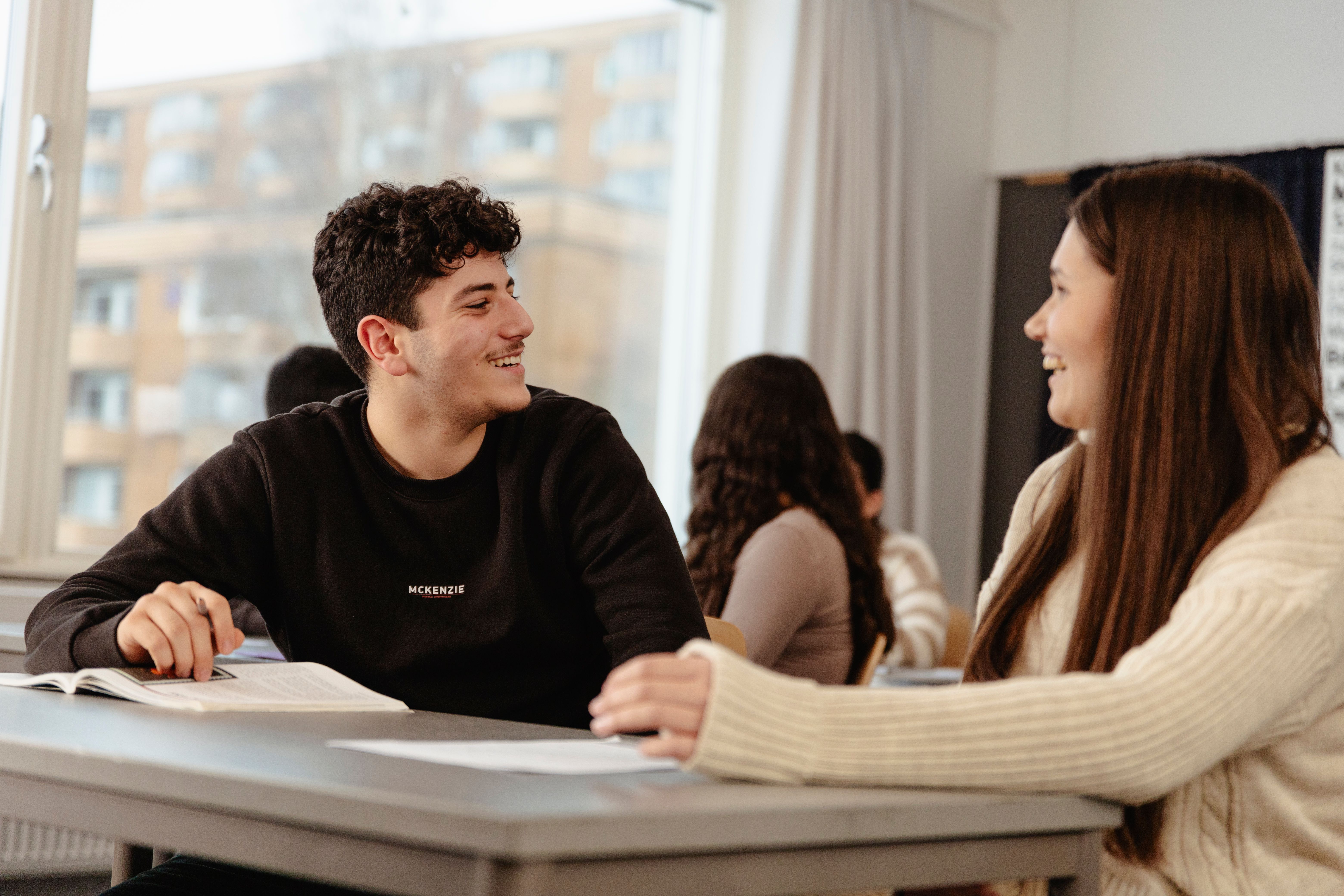 Two people sitting at a table and looking at each other, smiling and talking