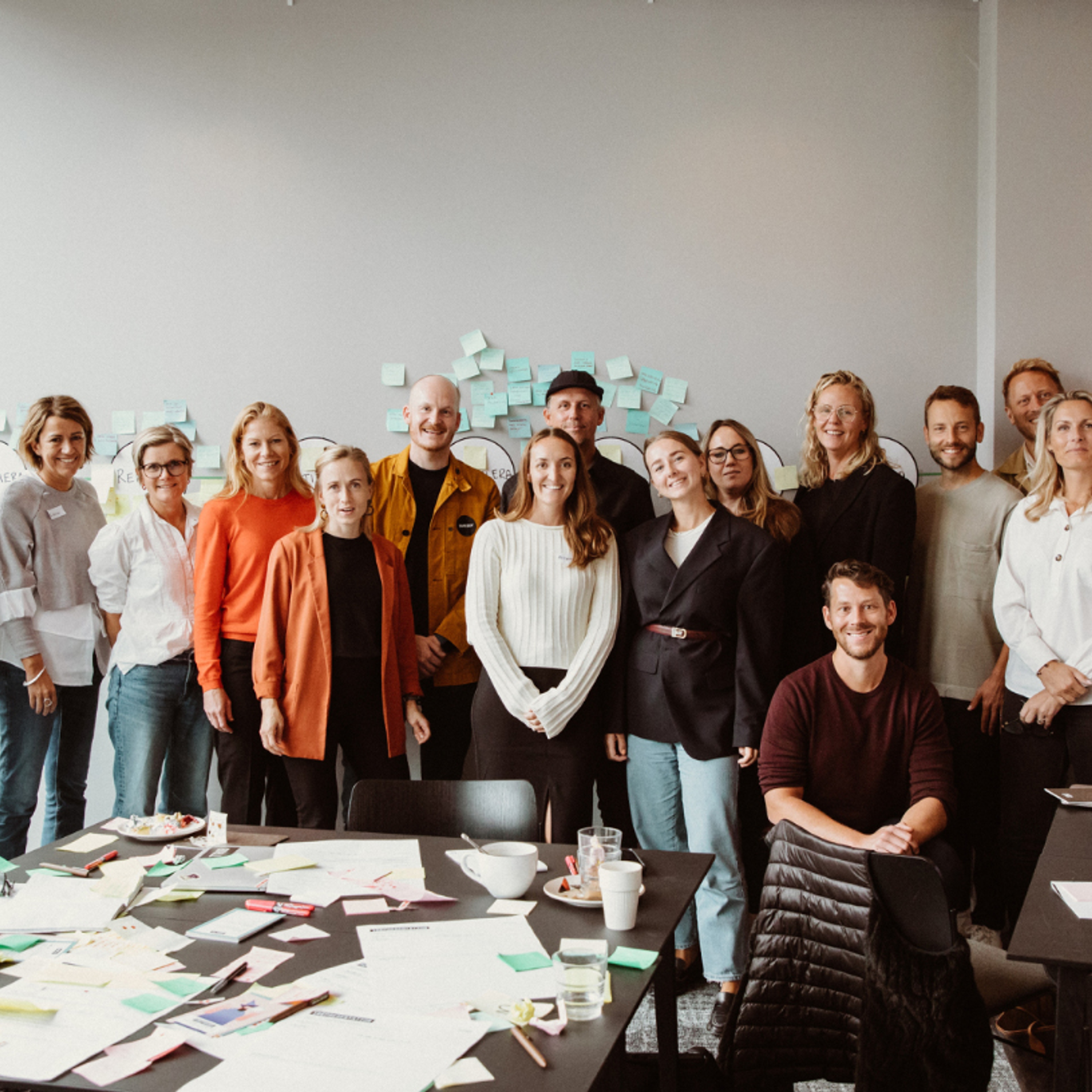 Grupp människor står framför en vägg och poserar mot kameran.