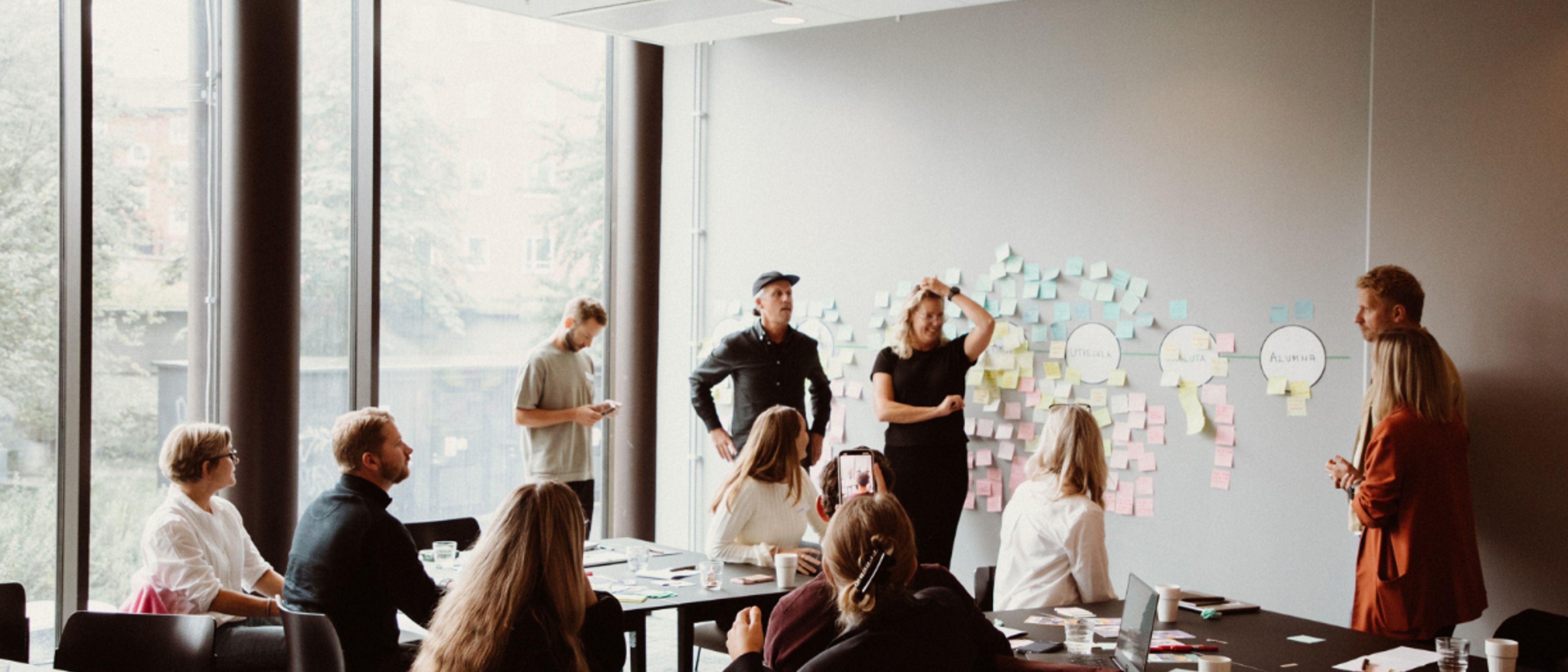 Many people standing in front of a whiteboard and having a workshop.