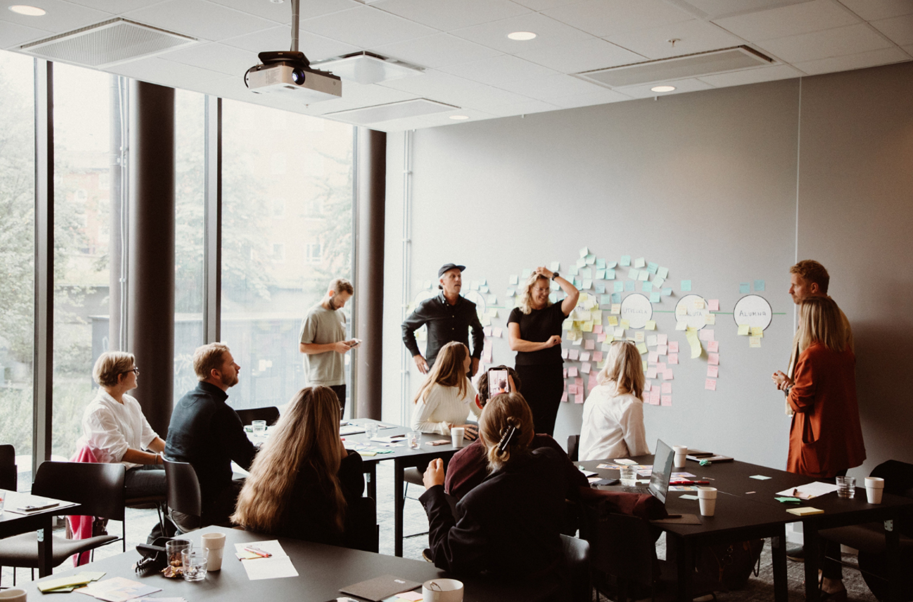 Many people standing in front of a whiteboard and having a workshop.