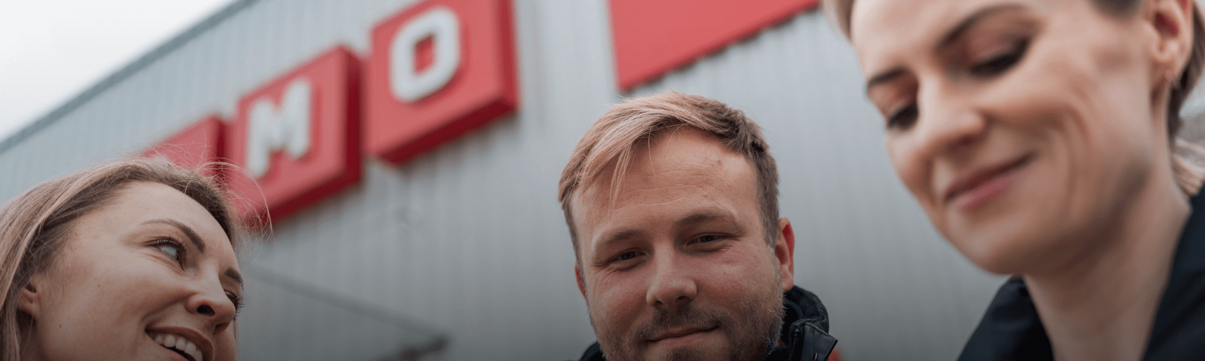 Three people standing outside a Cramo store