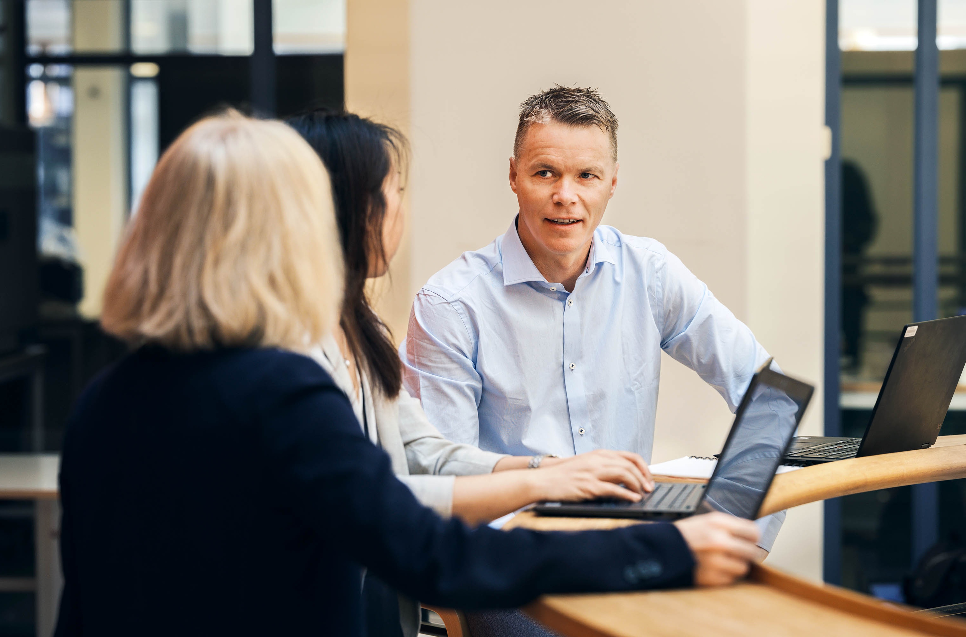People talking at a table with a computer