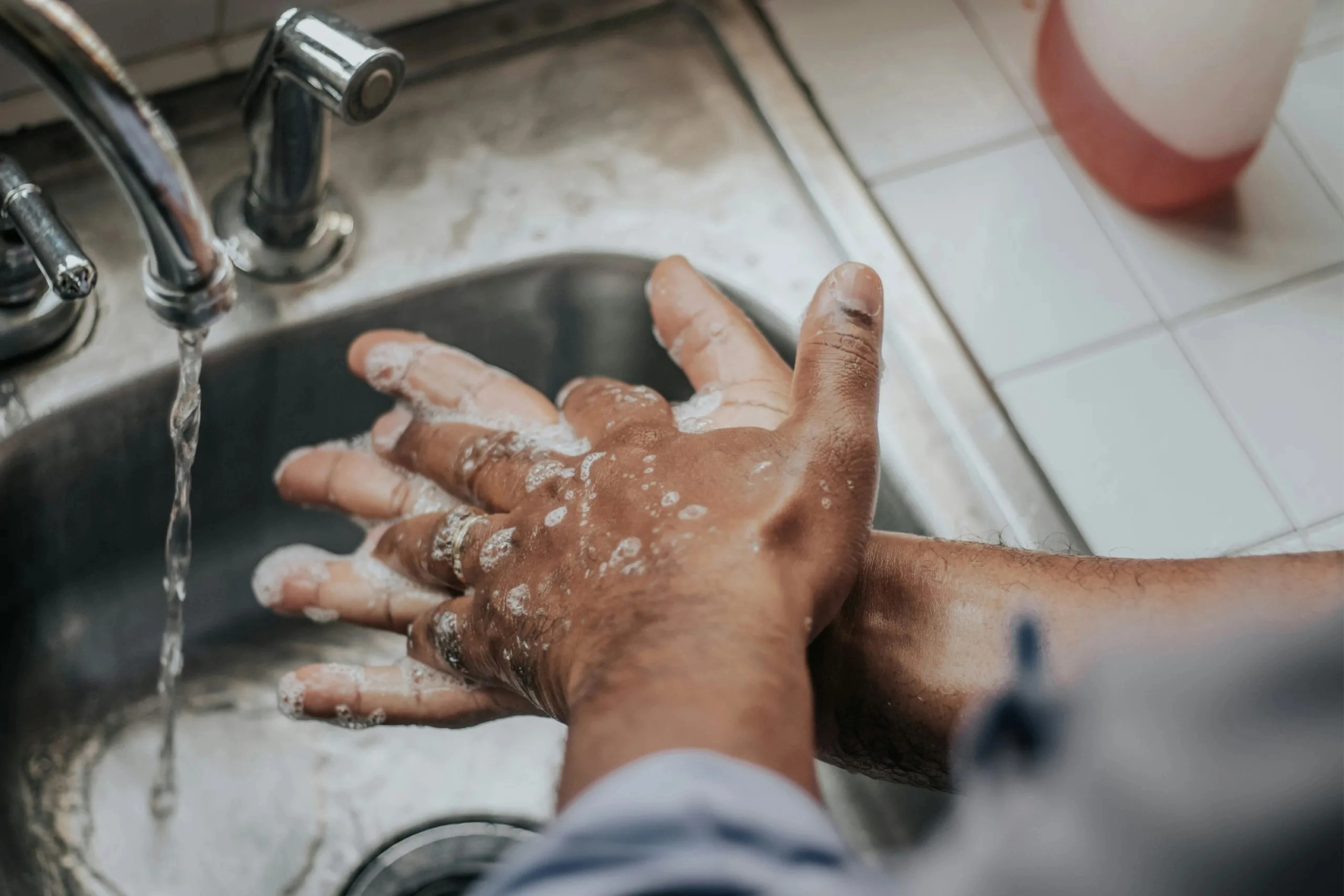 Person washing hands with soap under running water.