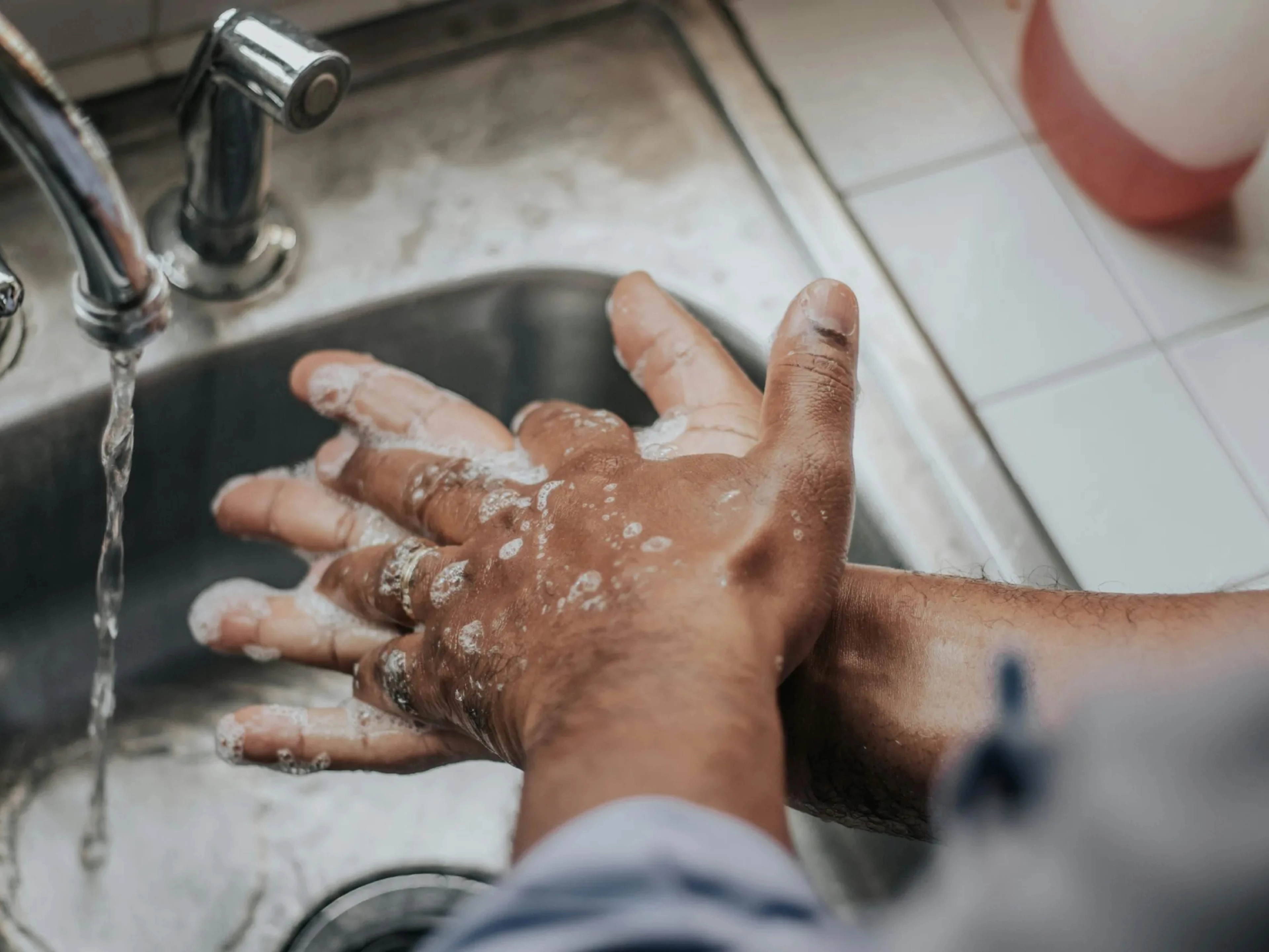 Person washing hands with soap under running water.
