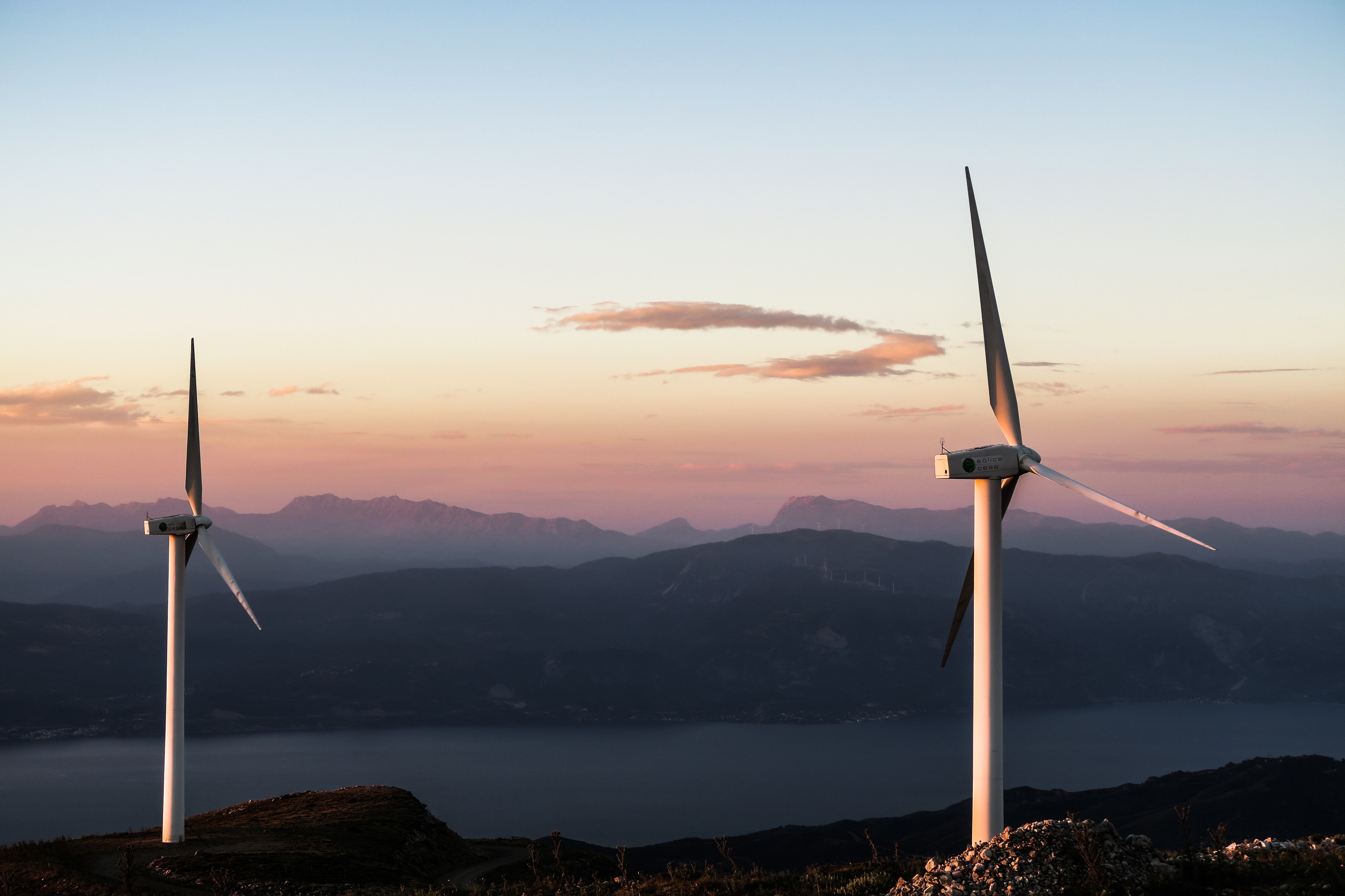 Two wind turbines in front of a sunrise sky