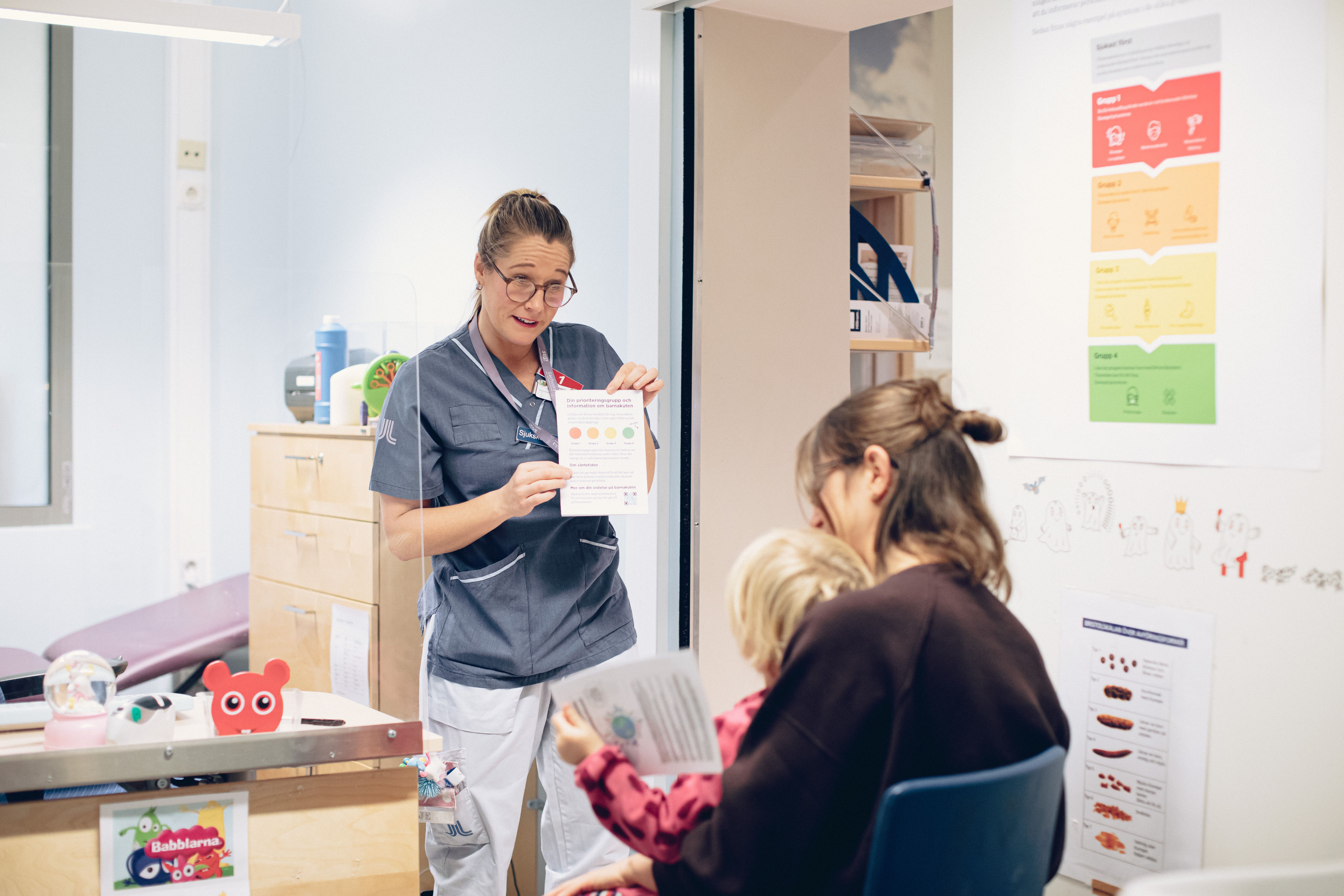 A nurse standing in front of a mother and a child in a hospital waiting room