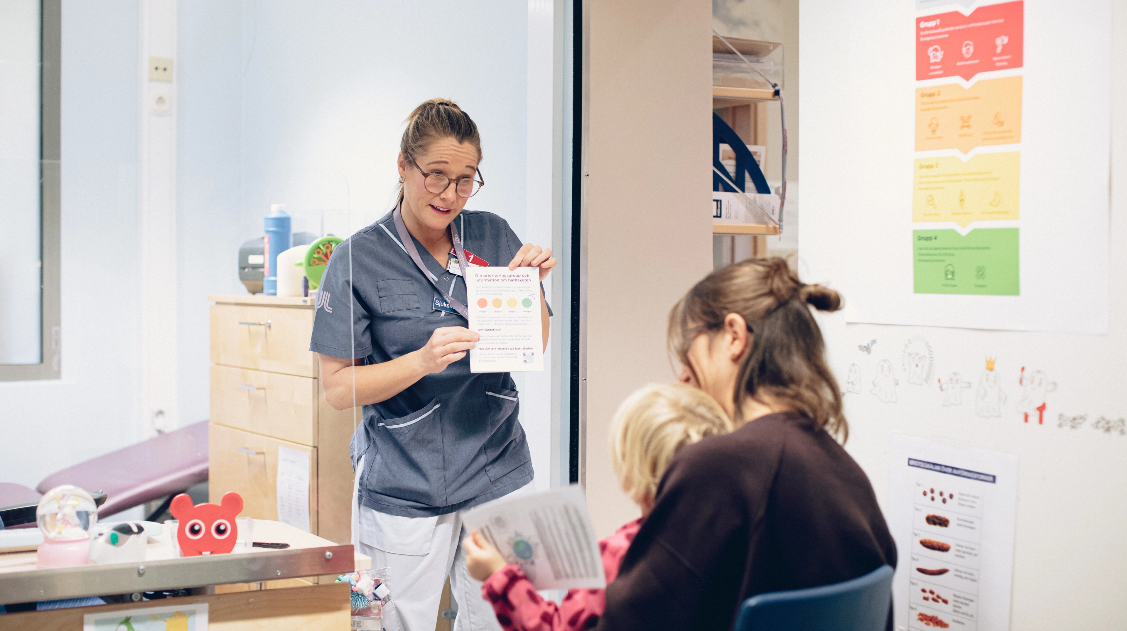 A nurse standing in front of a mother and a child in a hospital waiting room