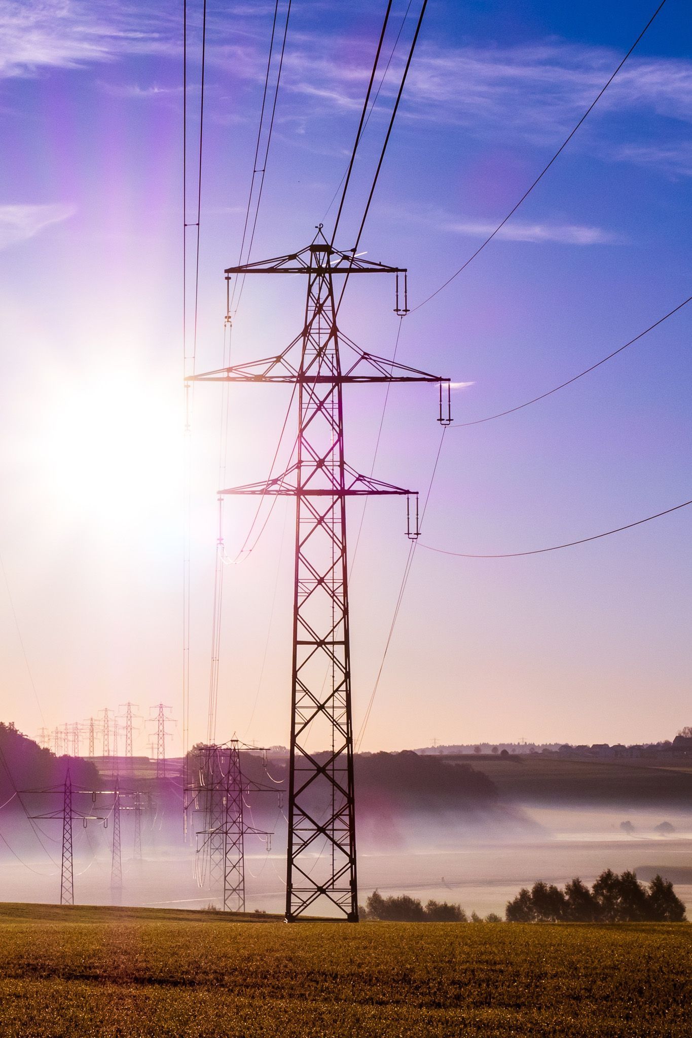 Power line towards a blue sunny sky with low dim banks 