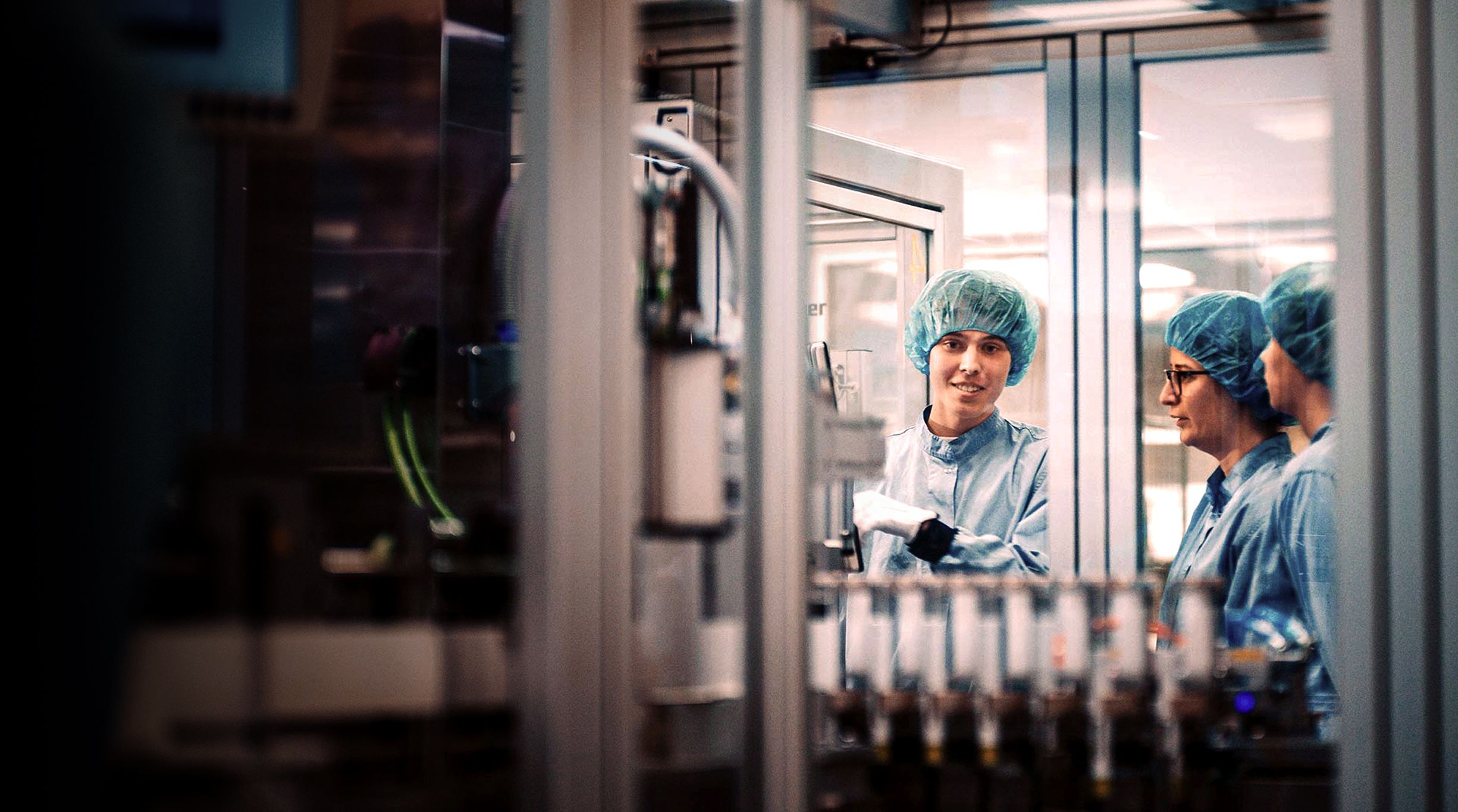 Two people looking at a woman who is working at a machine