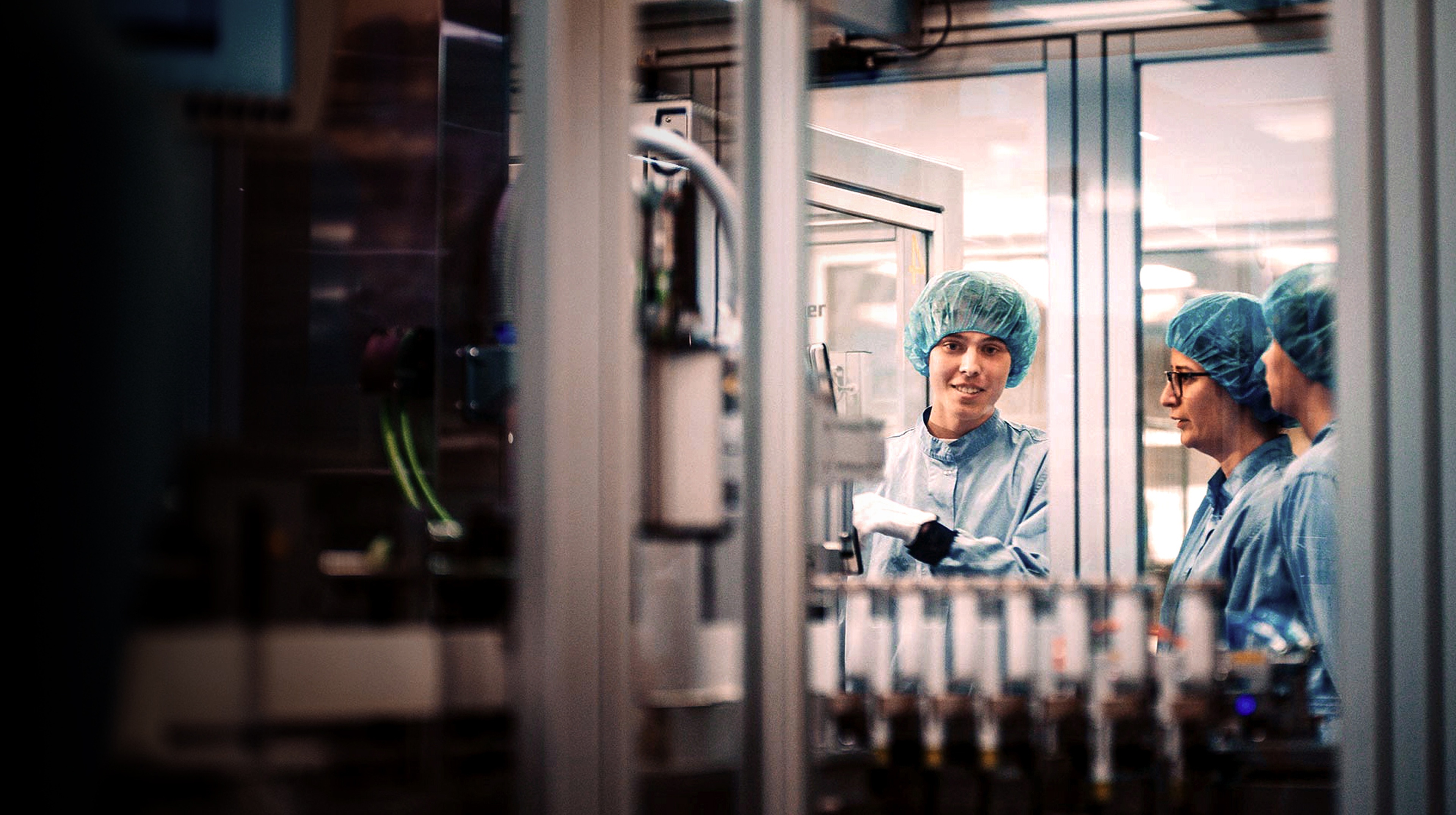 Two people looking at a woman who is working at a machine