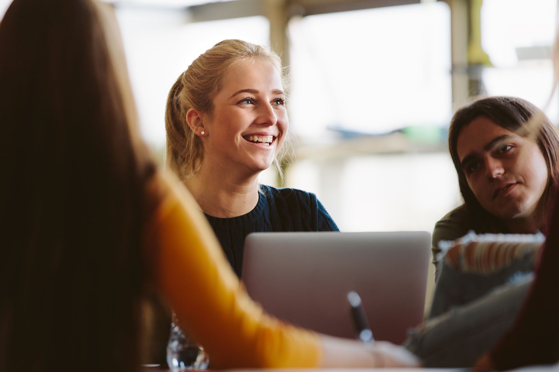 Three women smiling in front of a laptop