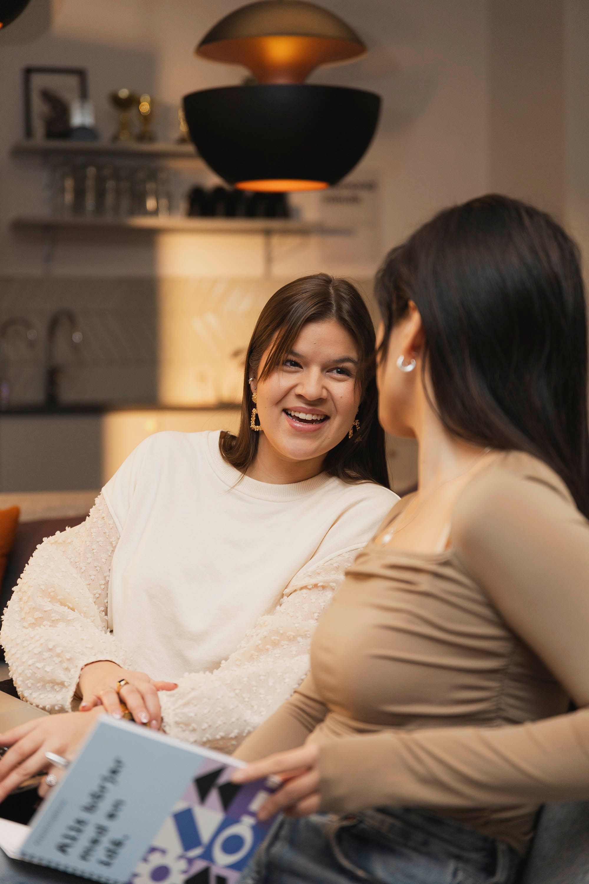 Two women sitting beside each other and smiling