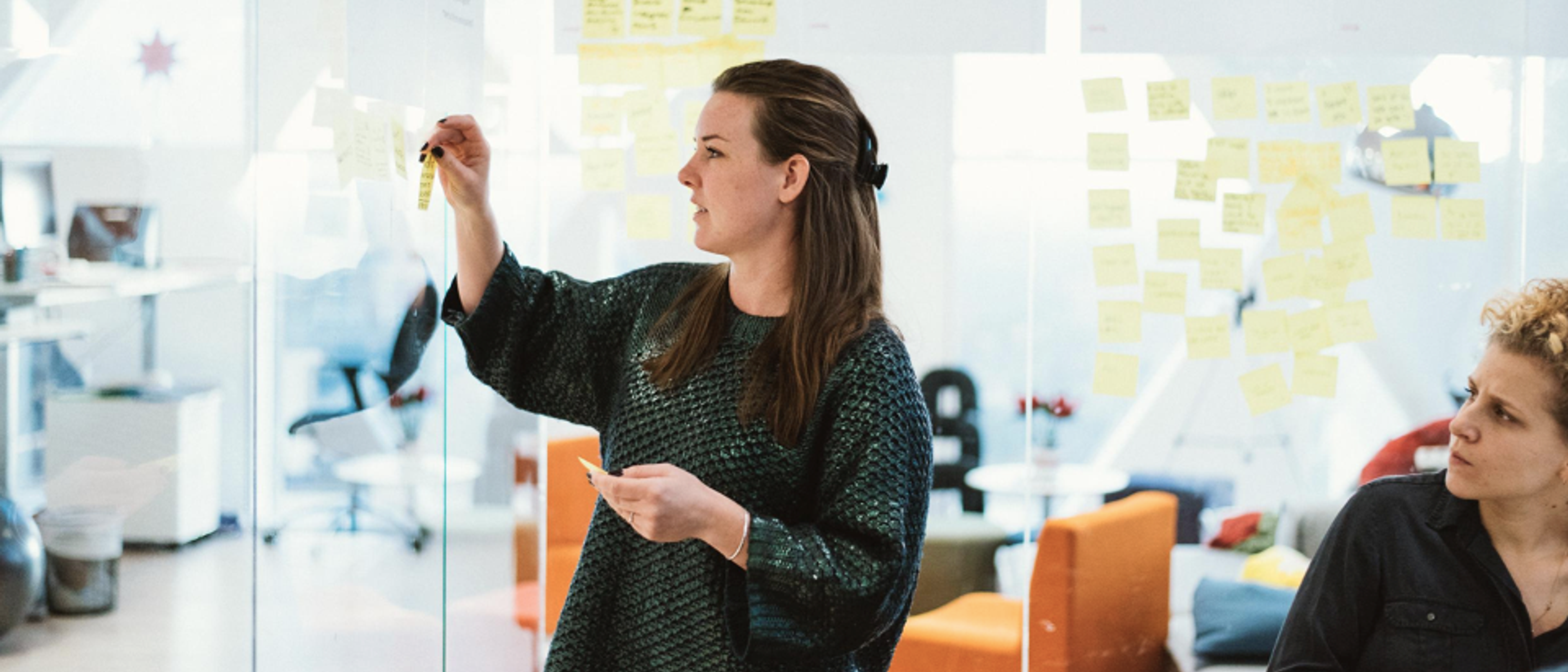 A women putting up a post-it note on a glass wall