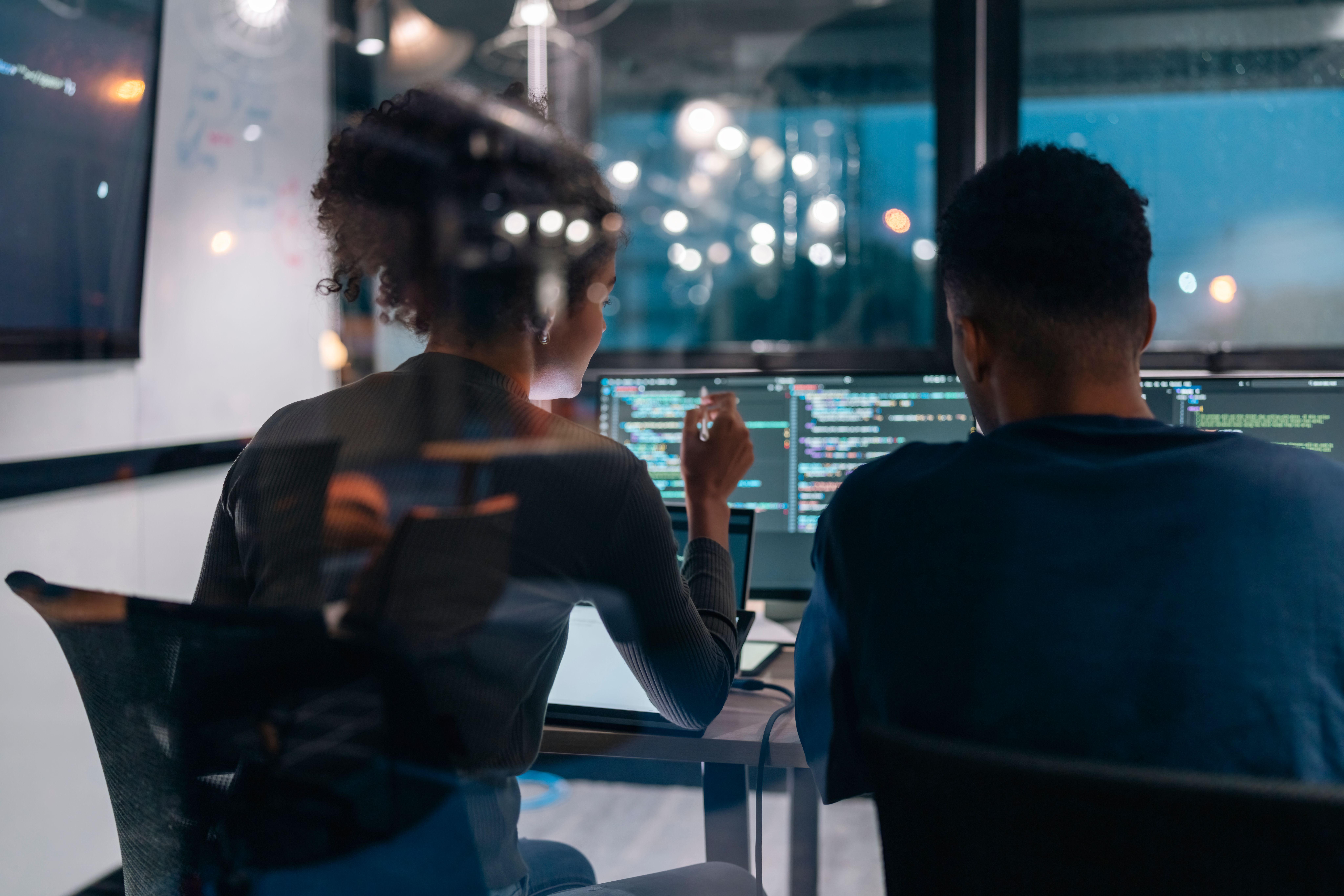 Two person sitting in front of computer screens
