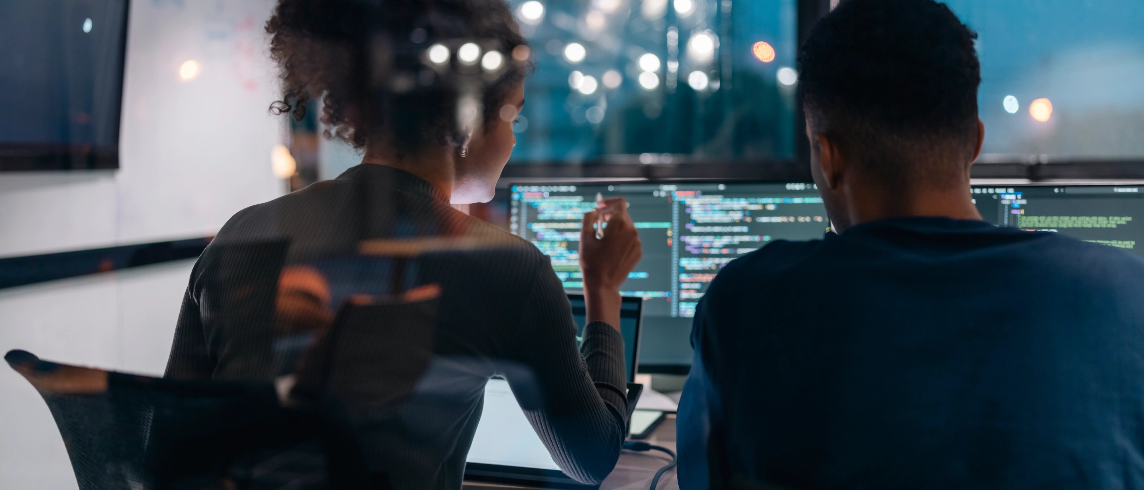 Two person sitting in front of computer screens