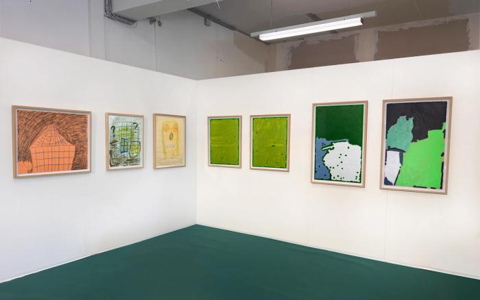 seven artworks on display in a booth. the artworks are framed drawings and paintings, many abstract, and some with figures and images.