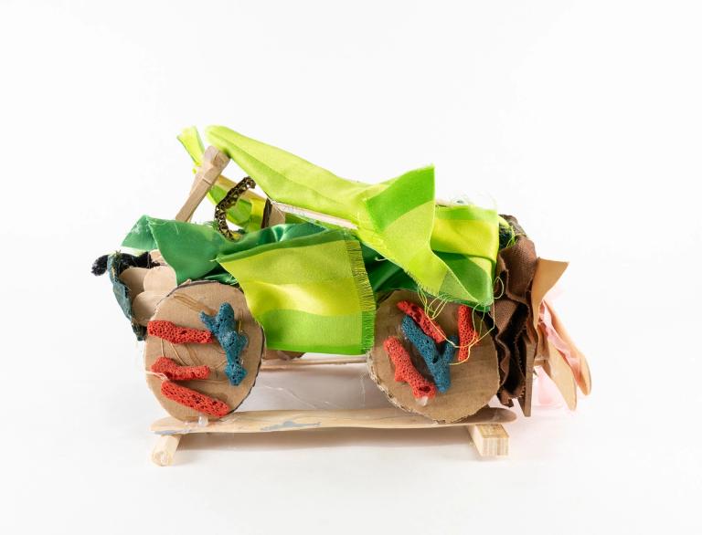 A mixed media sculpture containing lime green fabrics, cardboard, and wood.