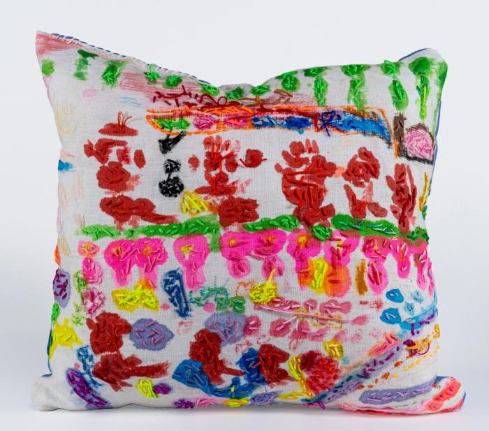 a very colorful pillow with many small shapes that are loosely floral with embroidery over very liquid feeling paint application