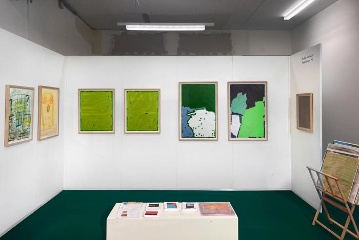 seven artworks on display in a booth. the artworks are framed drawings and paintings, many abstract, and some with figures and images.