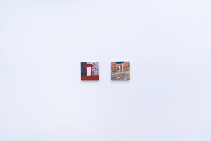 two small square shaped artworks on a white gallery wall. on left is a red and dark painting with a cup shaped form, and on right is a many colored landscape-like painting