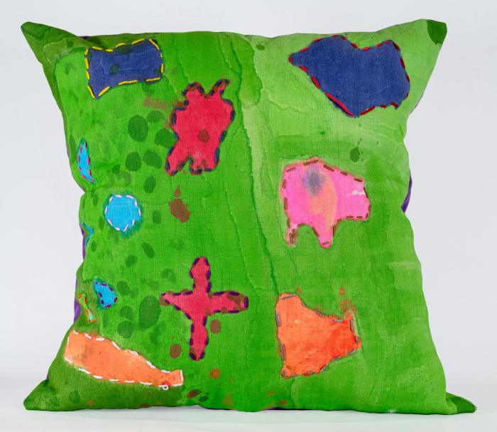 a green pillow with sections of red, orange, and pink in organic forms.