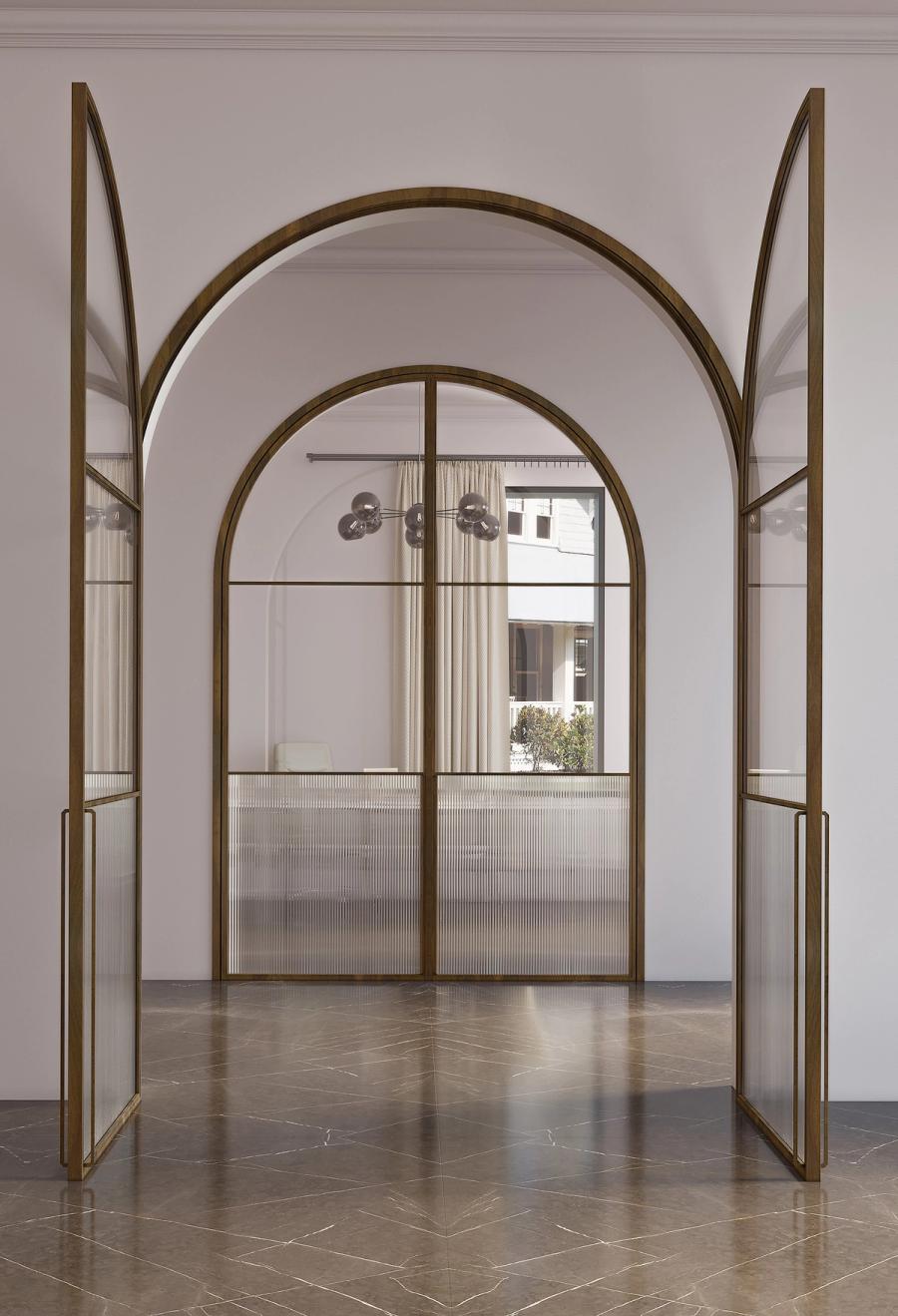 SUKI slim partition dividing an open-plan living and dining area, fine Ligne grid in matt aluminium, clear glass, natural light from one side casting soft grid 