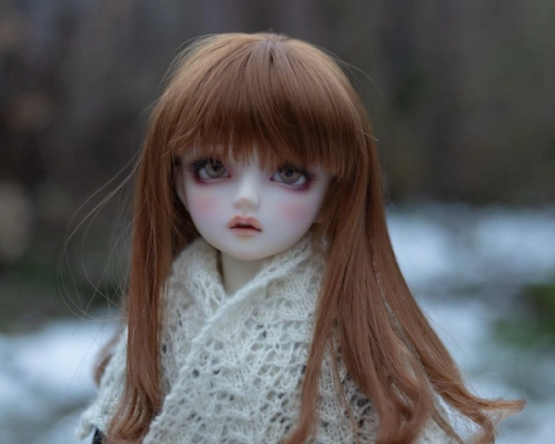 Portrait photo of a female ball-jointed doll with auburn hair, standing outside in the snow and wearing a cream knitted shawl.