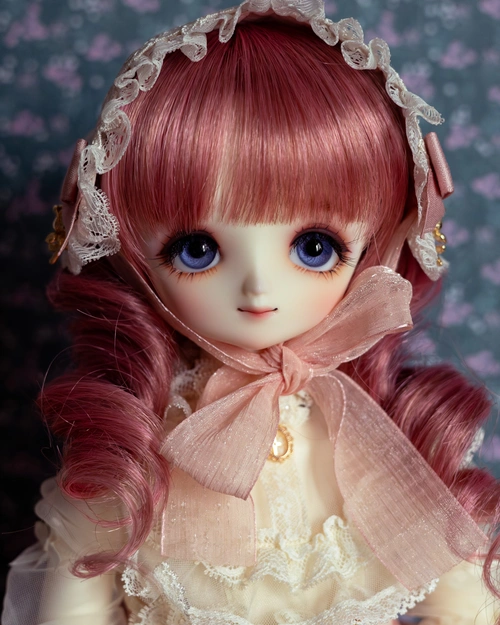 Portrait photo of a female ball-jointed doll with big blue eyes, a pink and white frilly outfit, and a pink wig with curls.