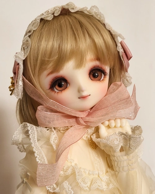 A ball-jointed doll with large eyes, wearing a frilly blouse and a lolita-style headdress.