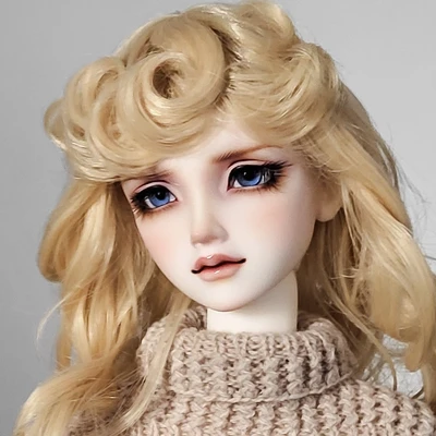 Female resin ball-jointed doll with long curly blond hair, a stern expression, blue eyes, wearing a knitted jumper.