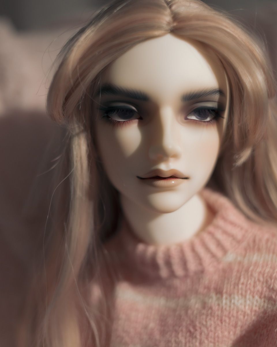 Close-up photo of a male ball-jointed doll with pale skin and long ash-pink hair. He wears a pink and white striped knitted sweater.