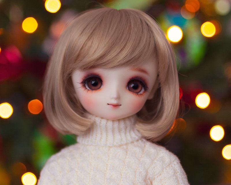 Female ball-jointed resin doll with shoulder-length light brown hair, big wide brown eyes, and a cream knitted sweater.