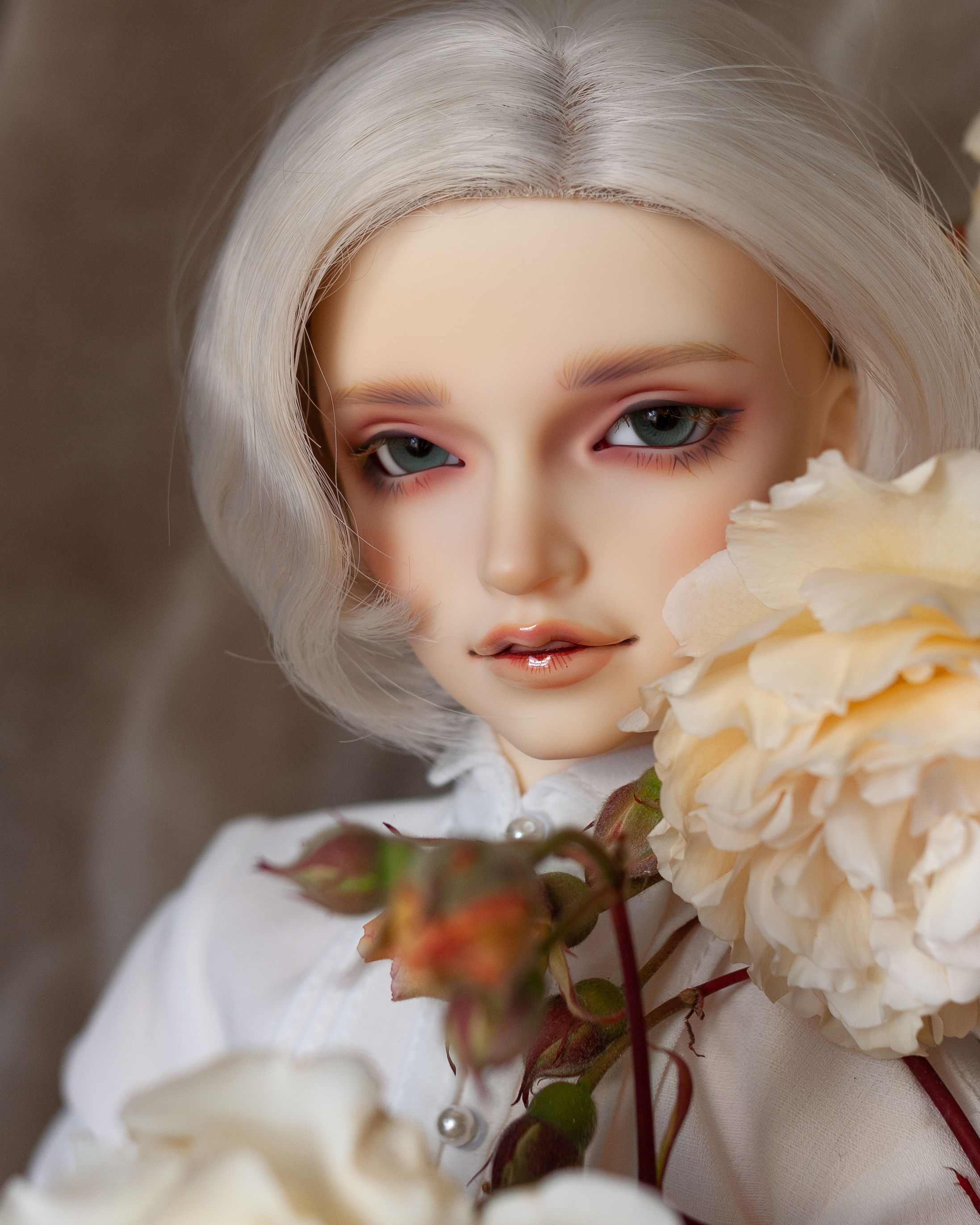 Male resin ball-jointed doll with chin-length white hair, wearing a white dress shirt, next to peach roses and rosebuds.