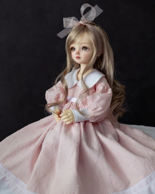 Female ball-jointed doll wearing a light pink full-skirted dress with puffy sleeves and a wide white collar.