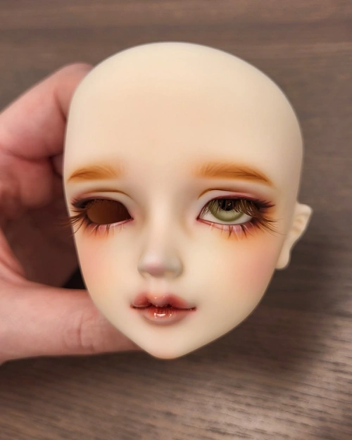 Female ball-jointed doll head with one pale green glass eye inserted.